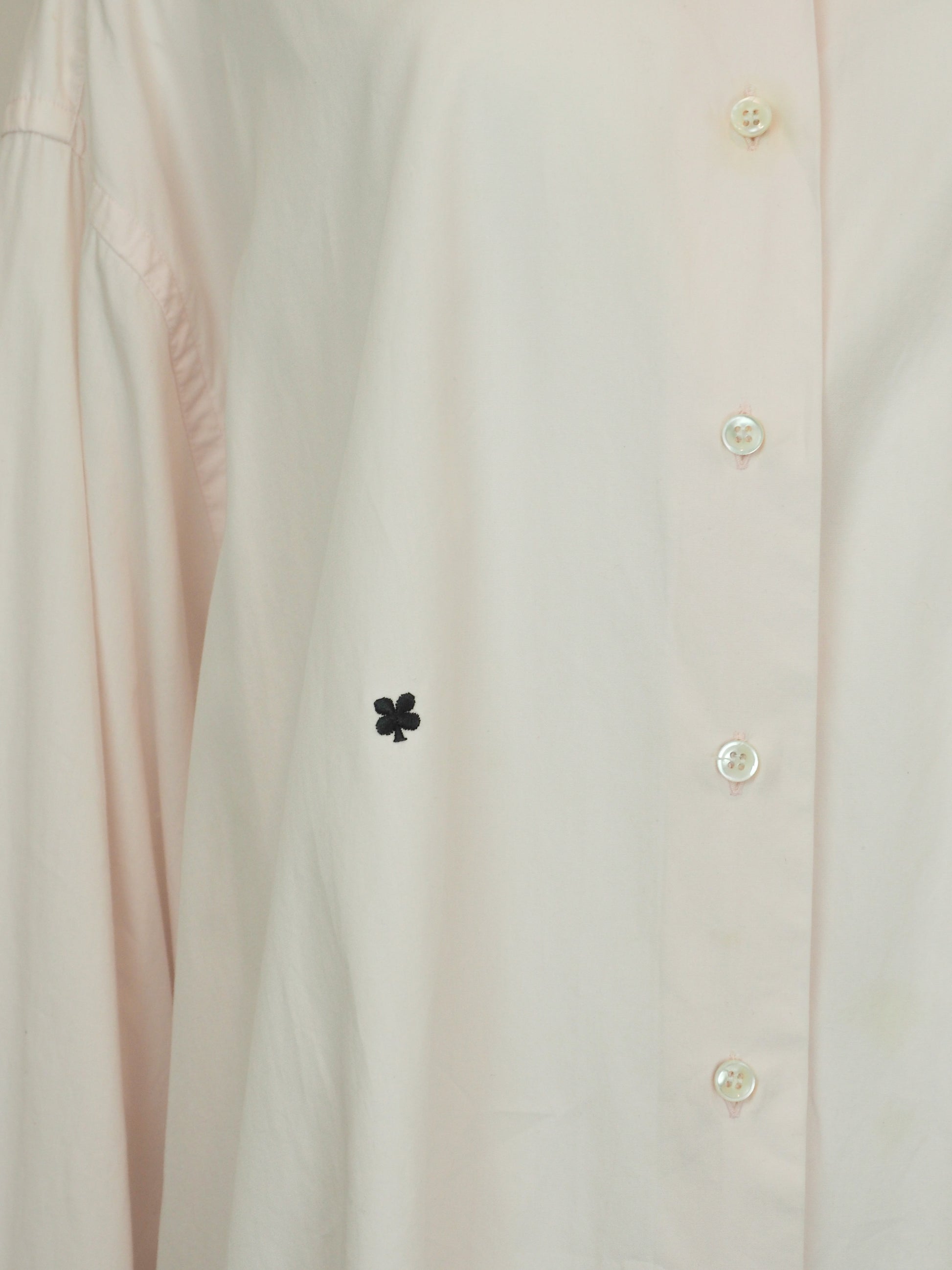 A vintage Maison Martin margiela 2001 pale blush pink oversized button-down shirt dress with a pointed collar, long sleeves, and a small black embroidered clover on the left chest
