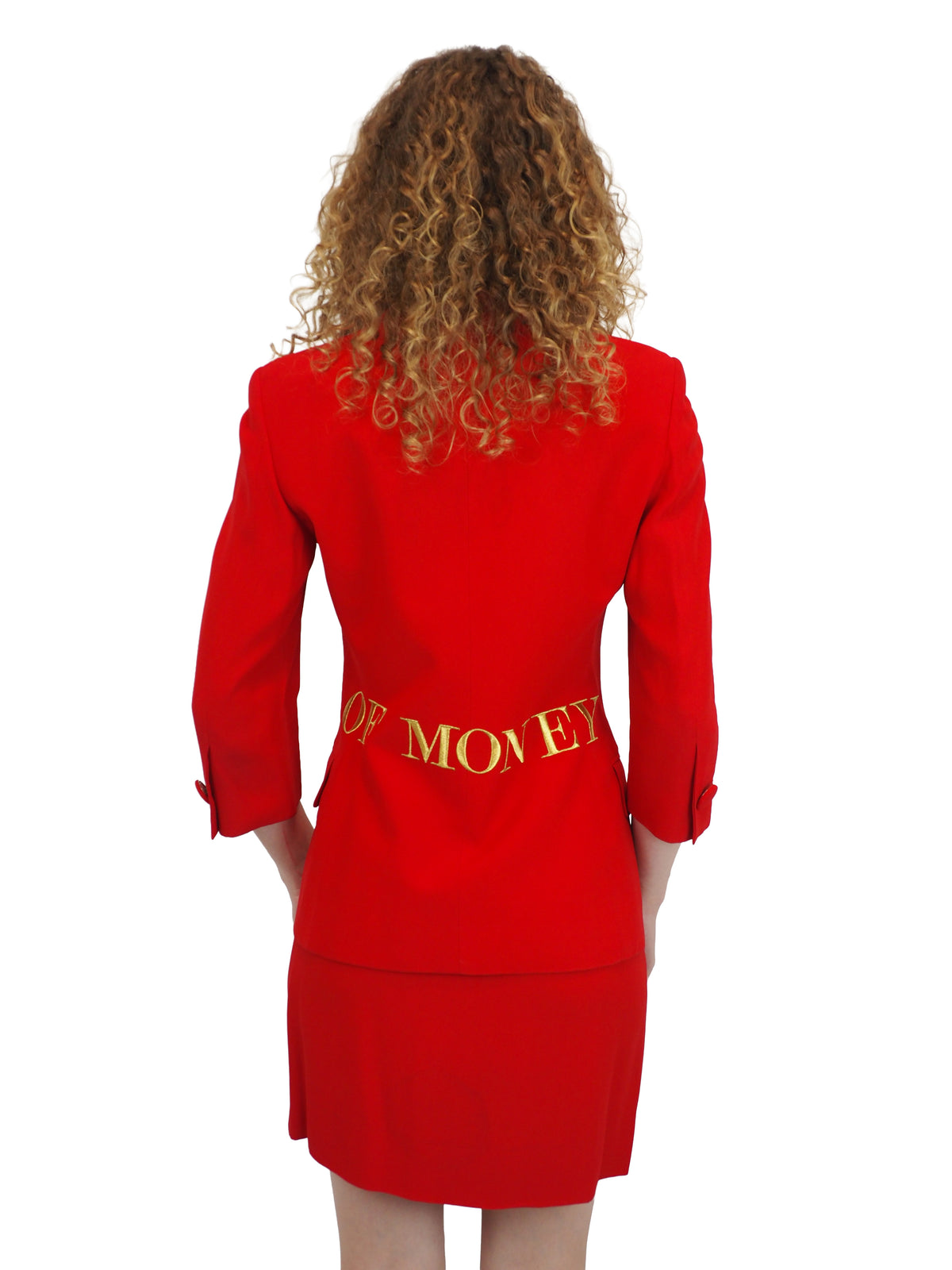 A vintage 1991 moschino bright red two-piece suit with gold lettering reading "waist of money"