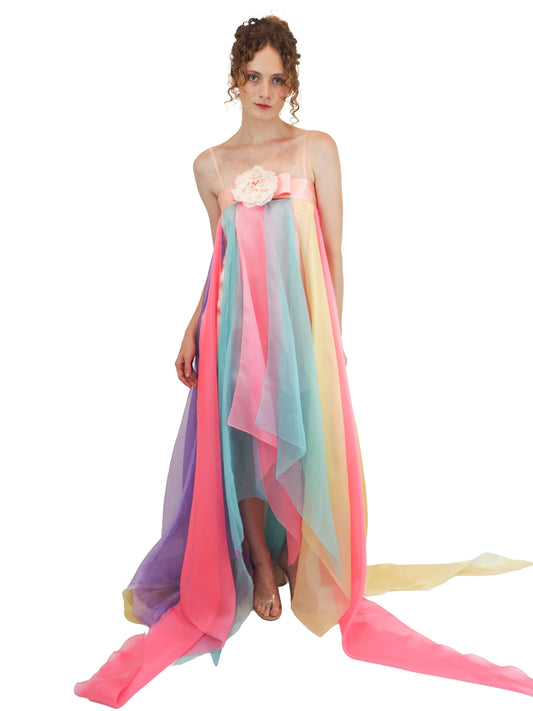 A vintage Pierre Cardin pastel rainbow tulle dress with a high-low hemline, a pink fabric flower at the bust, and a long flowing train 