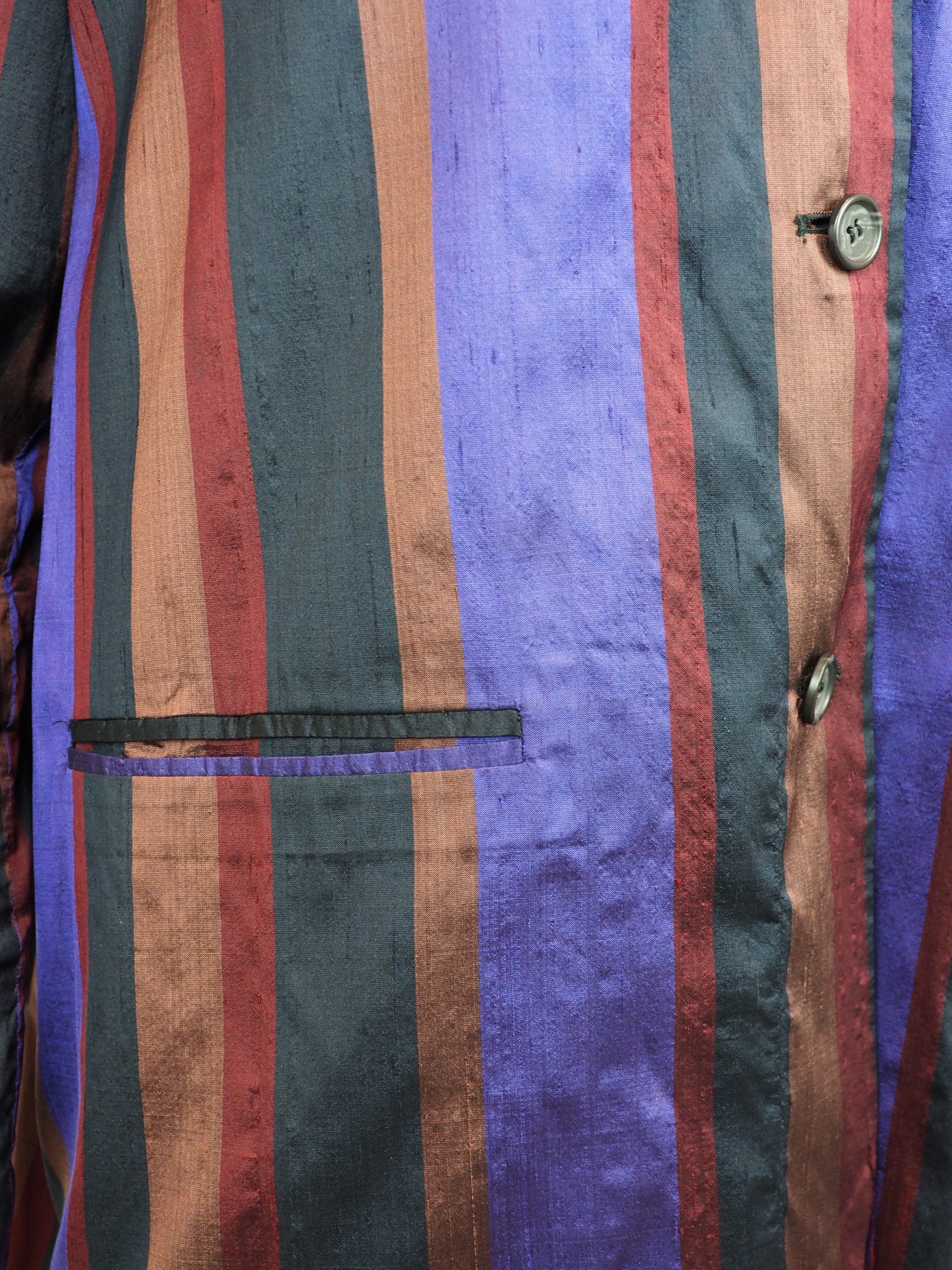 Romeo Gigli Vintage. A long-sleeve striped blazer with vertical stripes in purple, rust red, and black, featuring a three-button front closure and flap pockets.