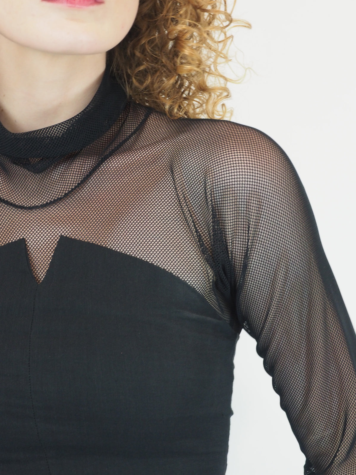 A vintage Romeo Gigli black long-sleeve mock neck dress with sheer mesh sleeves and a v neck bodice