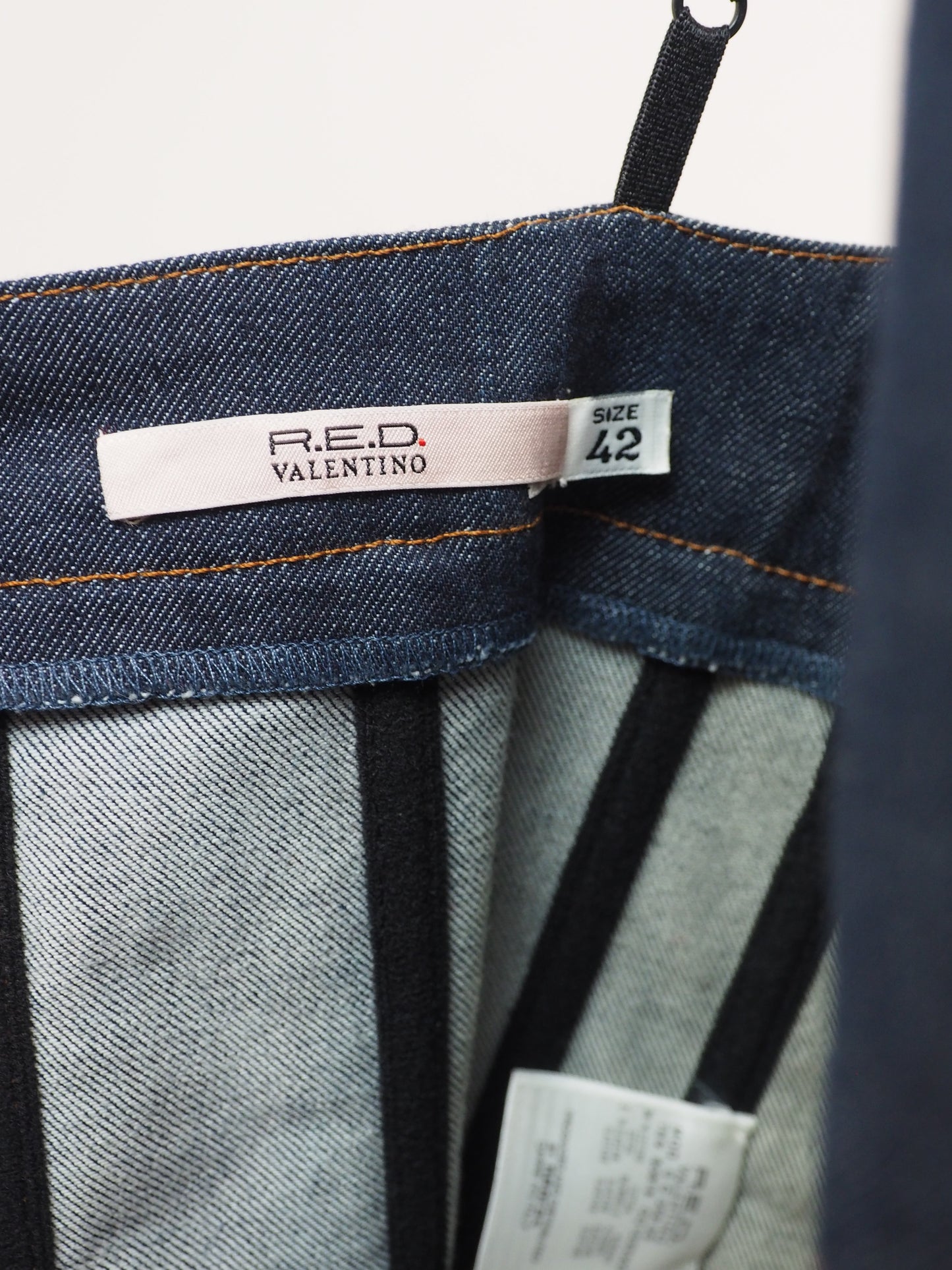 Close-up of the inner denim bustier showing the 'R.E.D. VALENTINO' brand label and a size '42' tag.