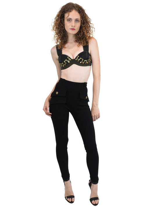 A vintage Versace black bralette with gold lettering and black skinny pants with gold button details