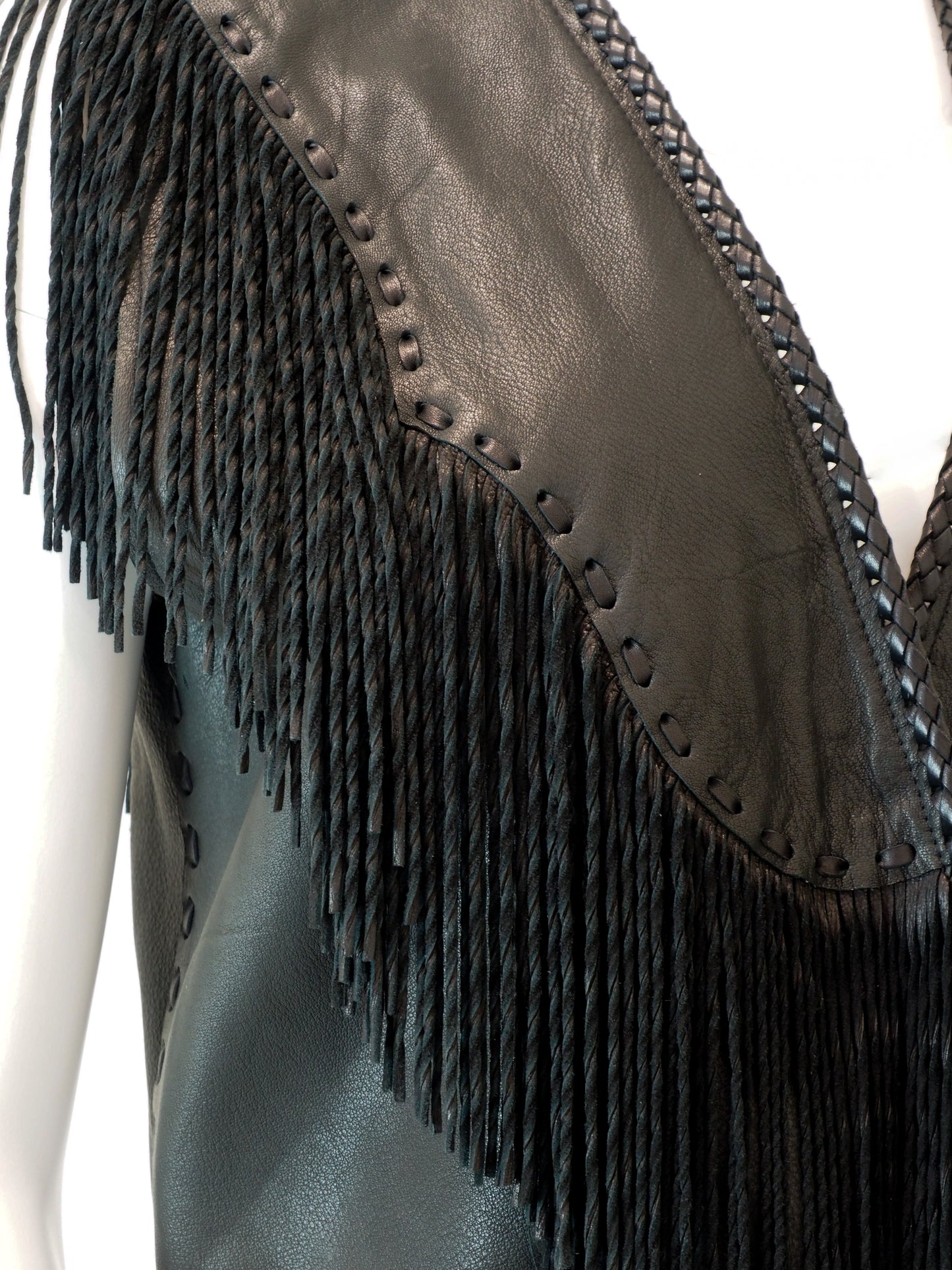 Close-up of a leather vest with fringe details on a white background
