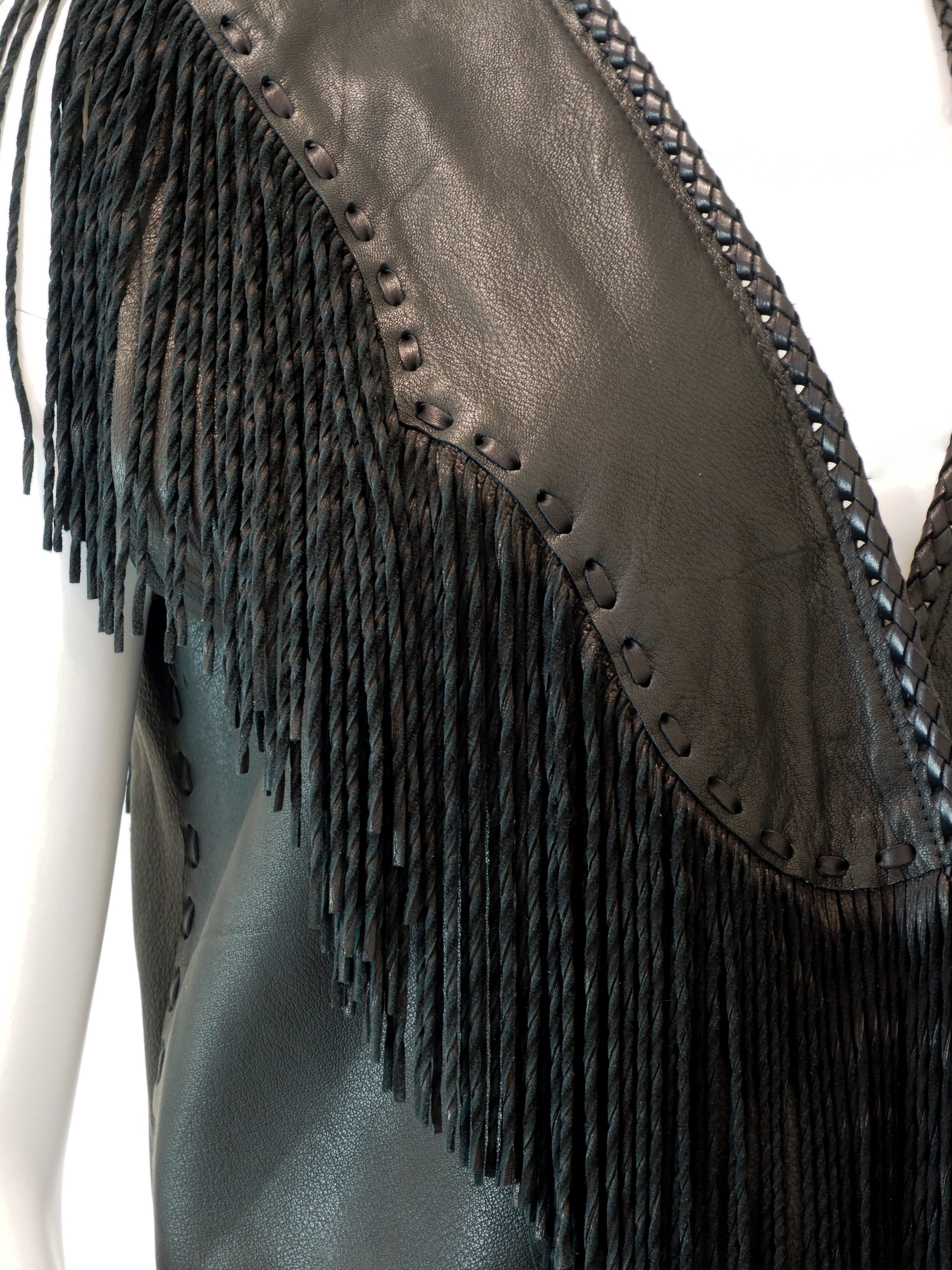 Close-up of a leather vest with fringe details on a white background