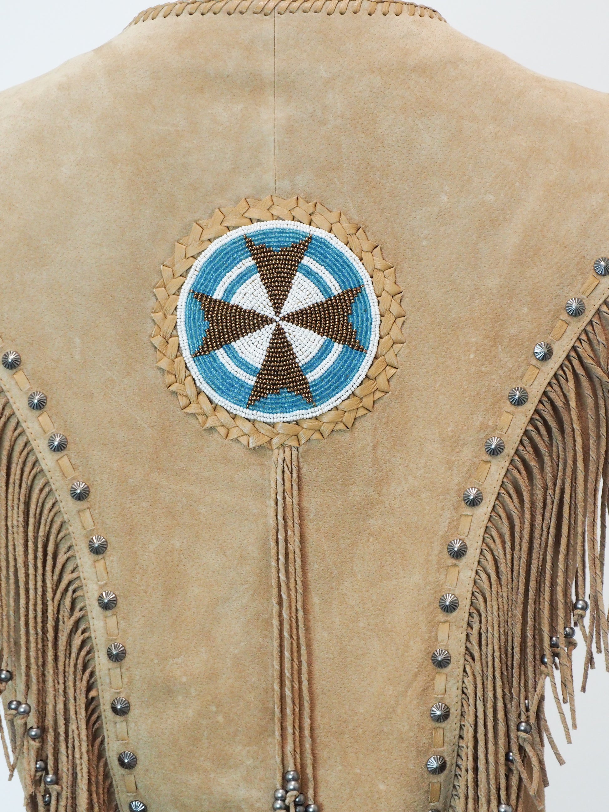 Beige leather jacket with decorative beadwork and fringes on a white background