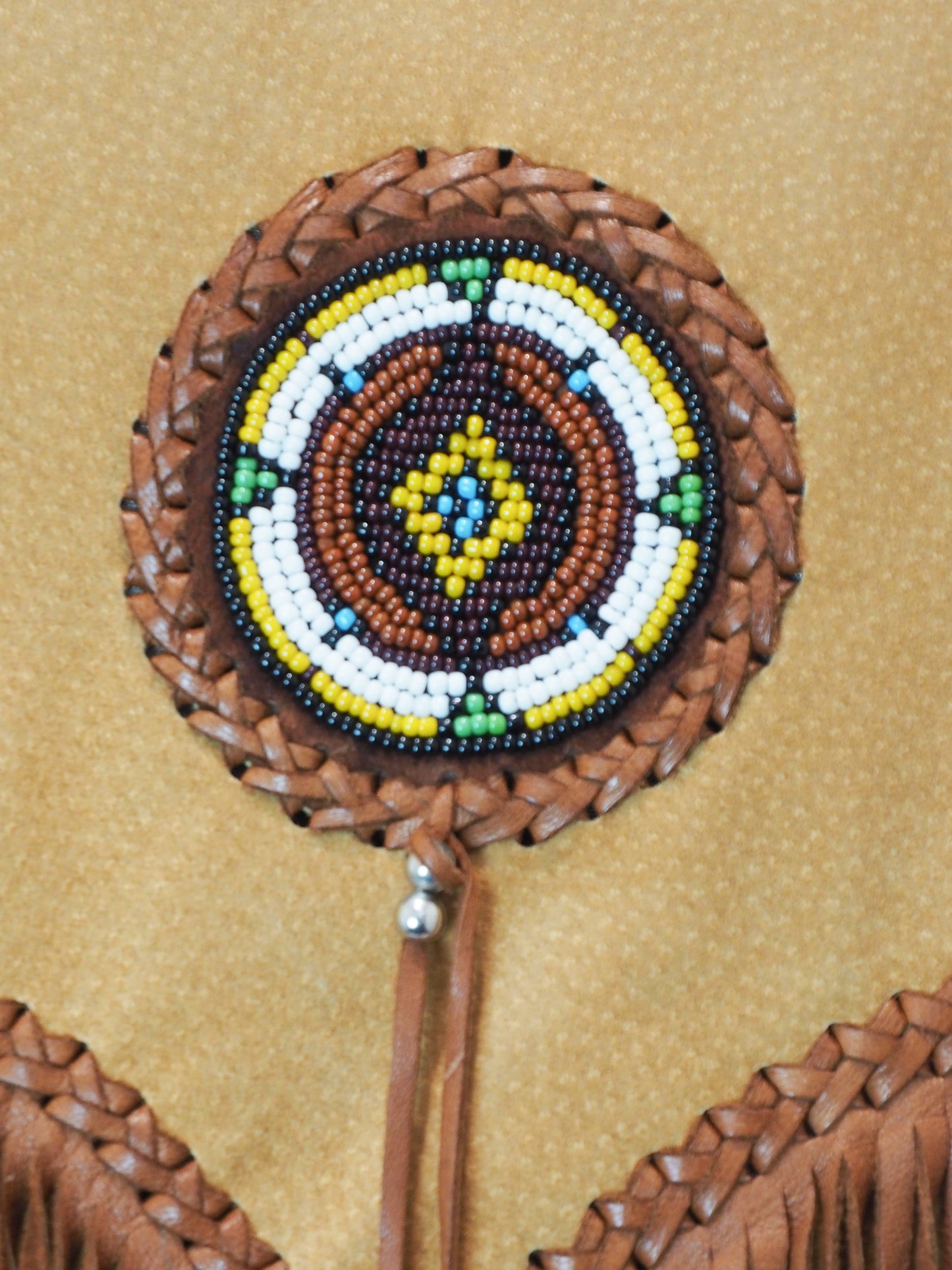 Decorative round object with braided brown design on a beige background