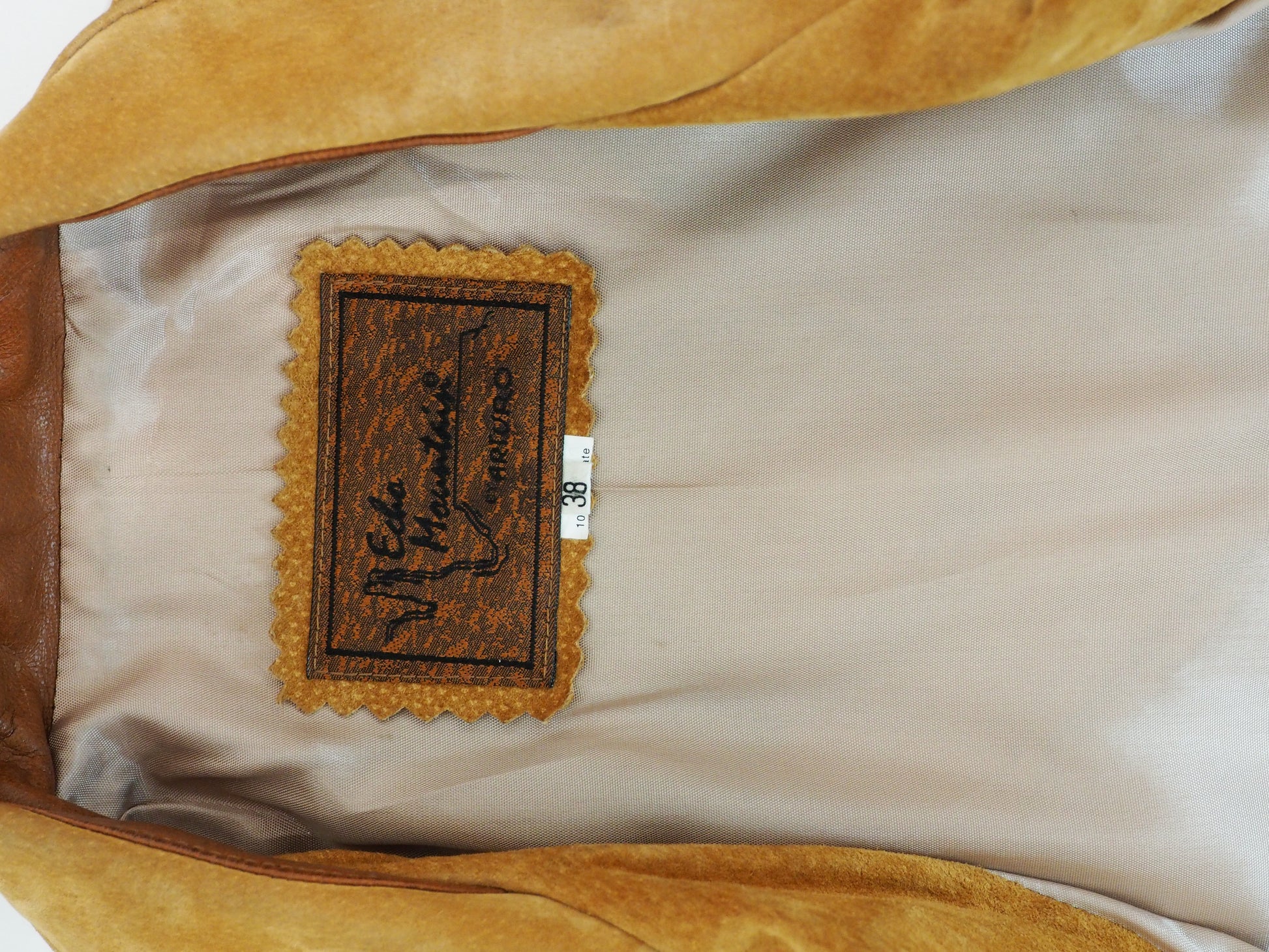 Close-up of a brown leather jacket lining with a brand label on a beige interior.