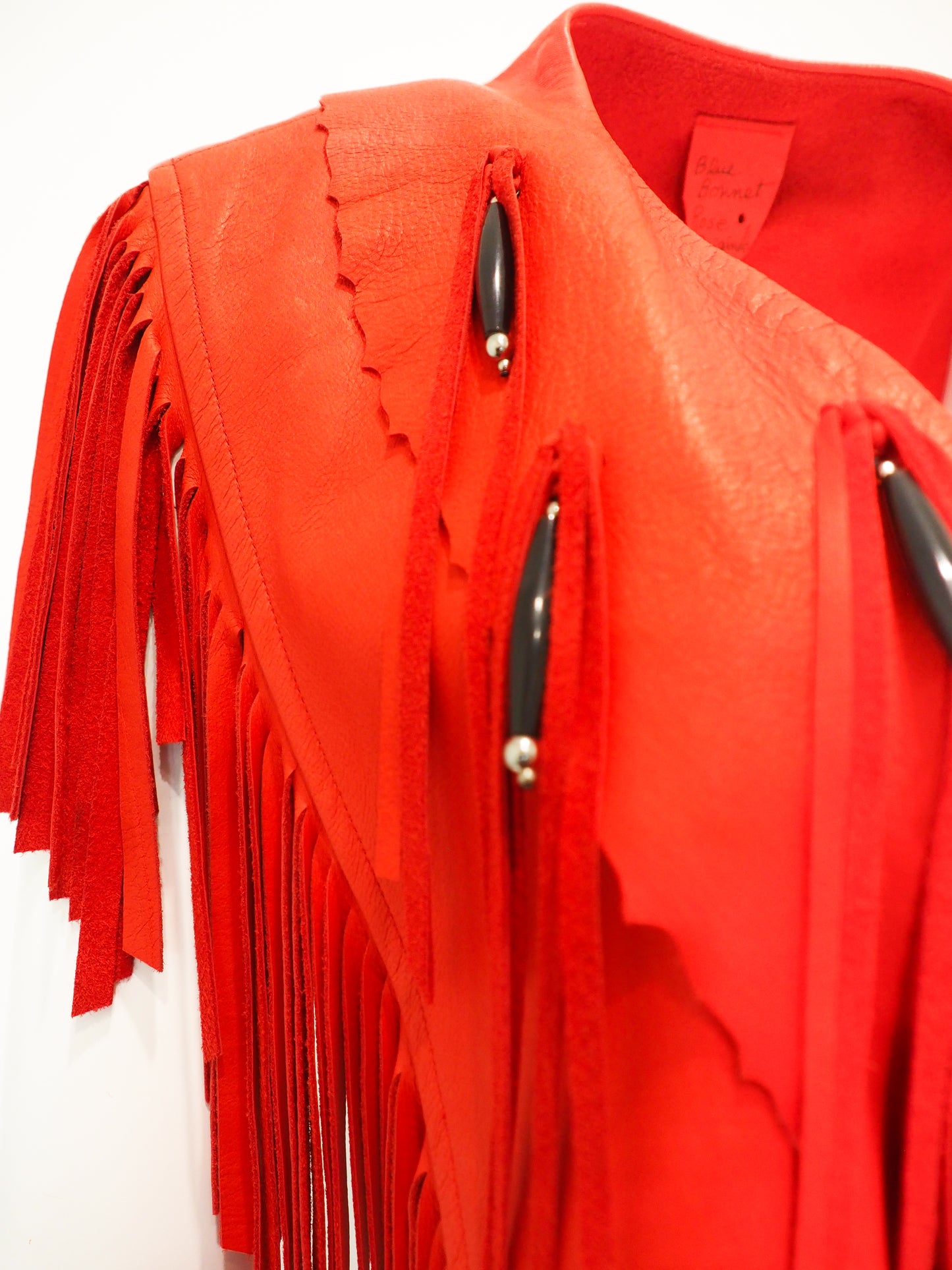 Red fringed jacket with beads on a white background
