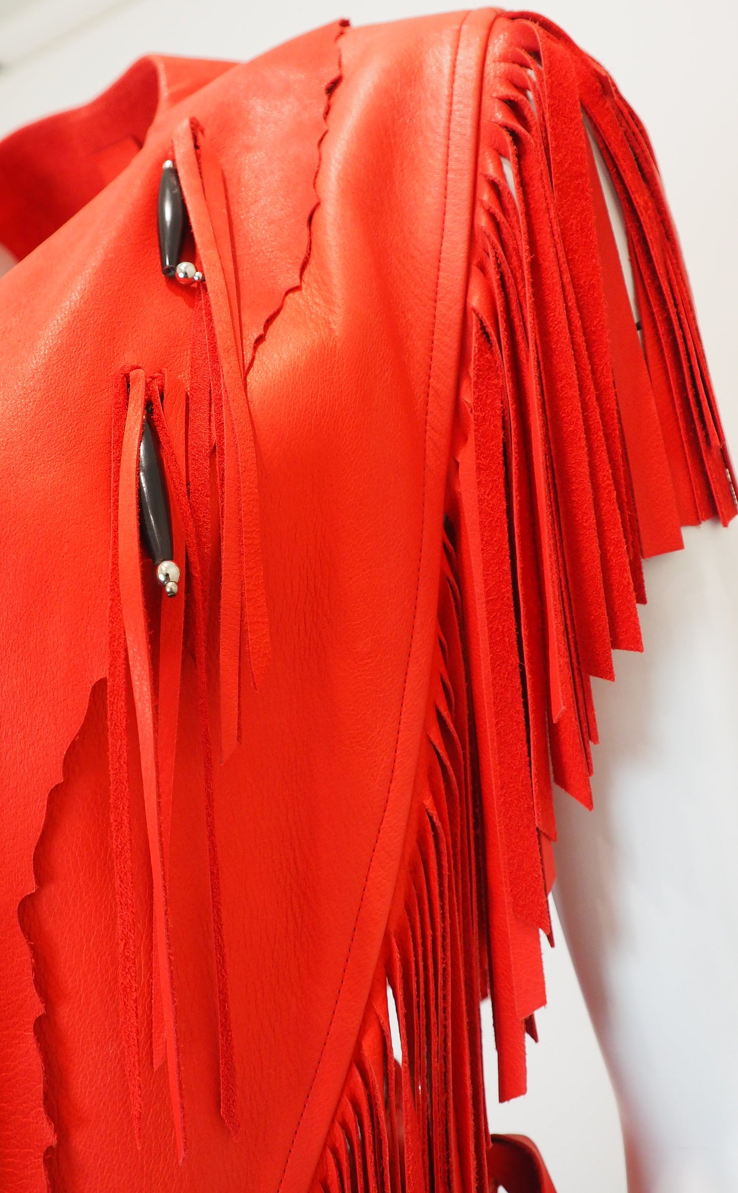 Red leather top with fringe details on a white background
