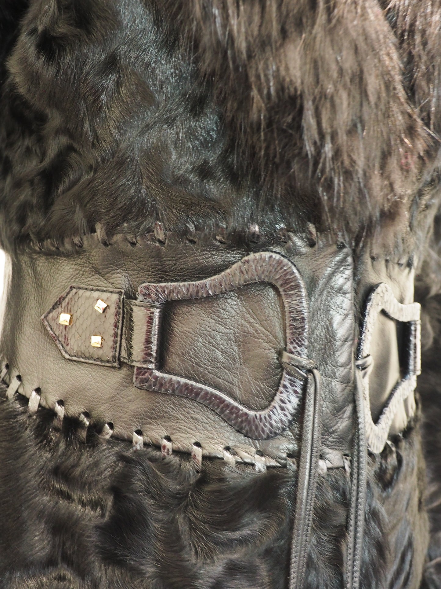 Close-up of a leather strap with decorative elements on a fur background