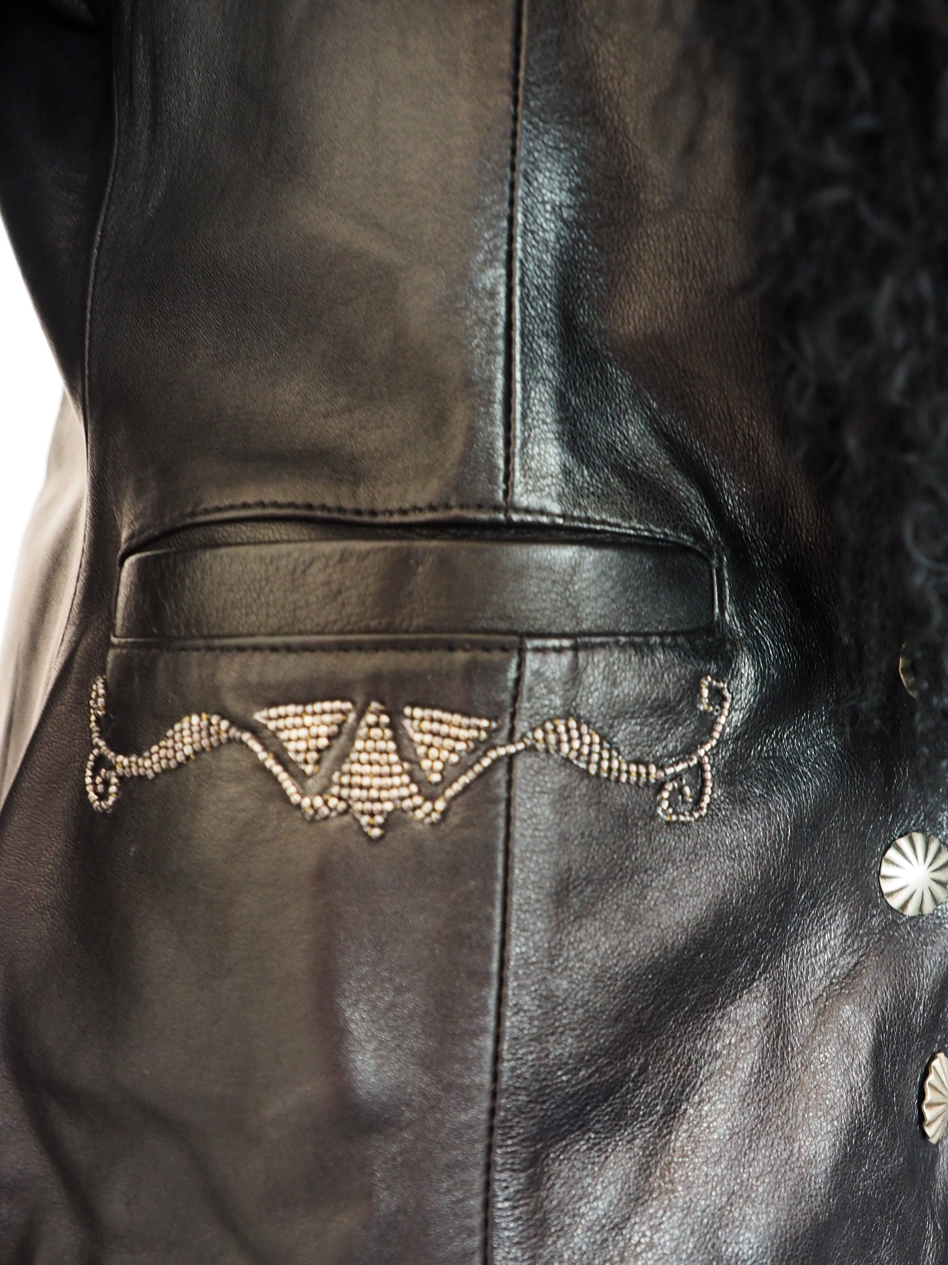Close-up of a black leather jacket with decorative elements.