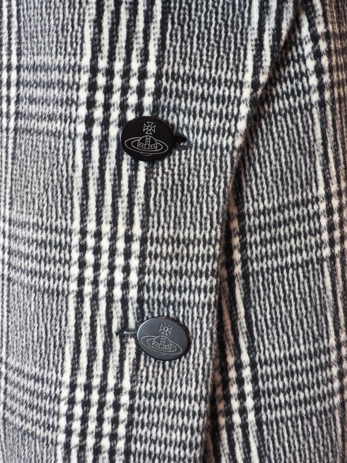 Close-up of a checkered fabric with buttons featuring the Vivienne Westwood logo.