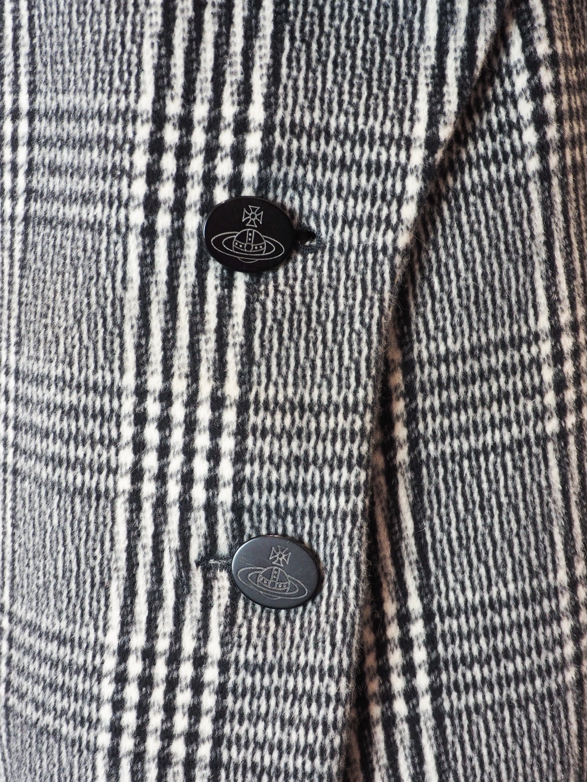 Close-up of a checkered fabric with buttons featuring the Vivienne Westwood logo.