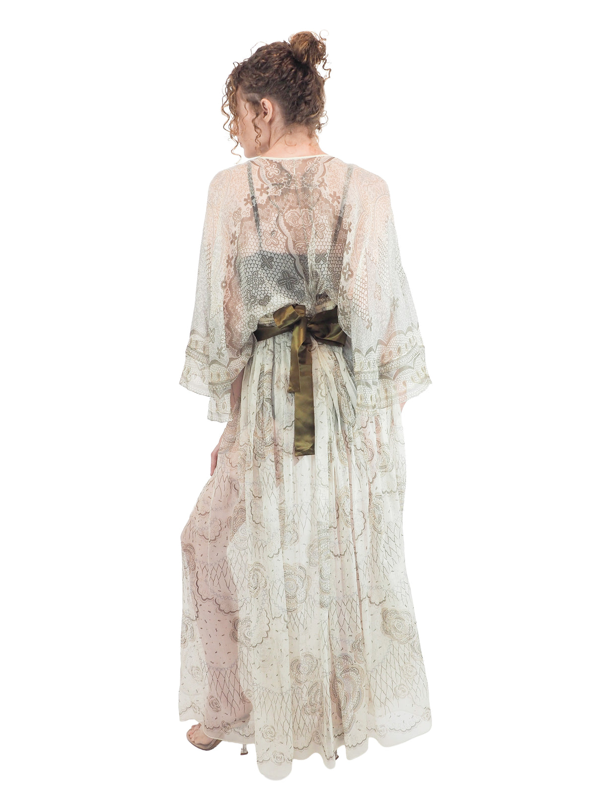 A vintage Zandra Rhodes long sheer maxi dress with a print detailing, wide three-quarter sleeves, and a wide dark olive green belt at the waist
