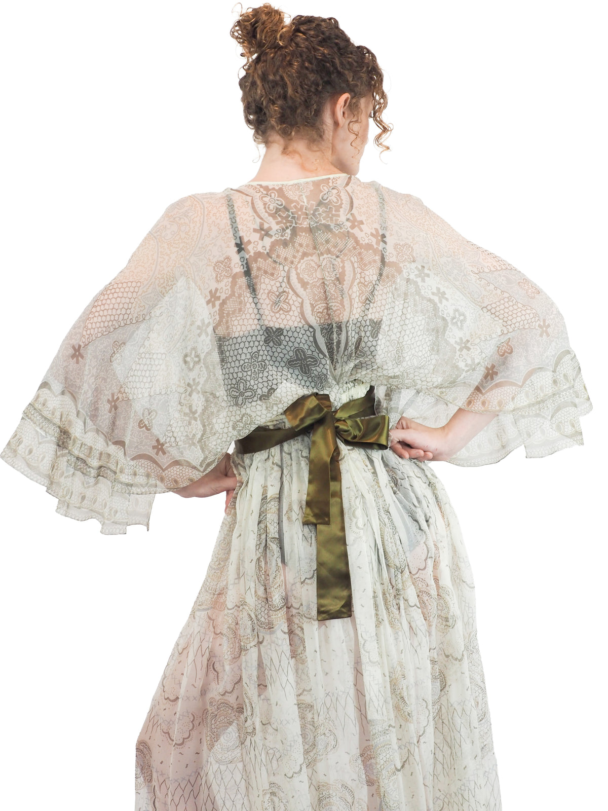 A vintage Zandra Rhodes long sheer maxi dress with a print detailing, wide three-quarter sleeves, and a wide dark olive green belt at the waist