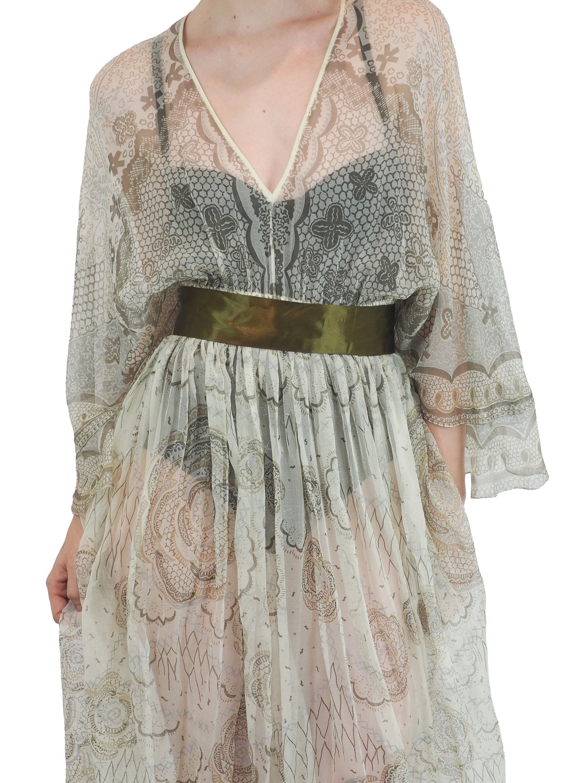 A vintage Zandra Rhodes long sheer maxi dress with a print detailing, wide three-quarter sleeves, and a wide dark olive green belt at the waist