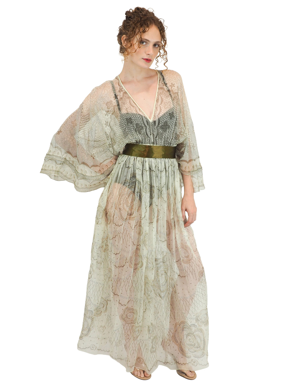 A vintage Zandra Rhodes long sheer maxi dress with a print detailing, wide three-quarter sleeves, and a wide dark olive green belt at the waist