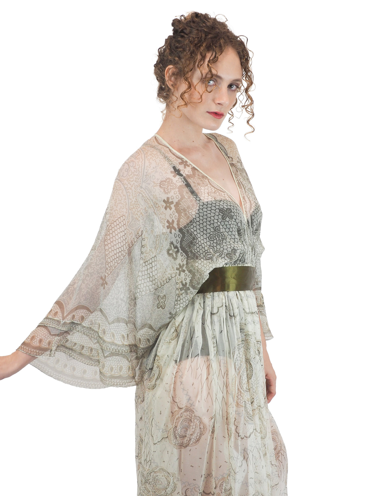 A vintage Zandra Rhodes long sheer maxi dress with a print detailing, wide three-quarter sleeves, and a wide dark olive green belt at the waist