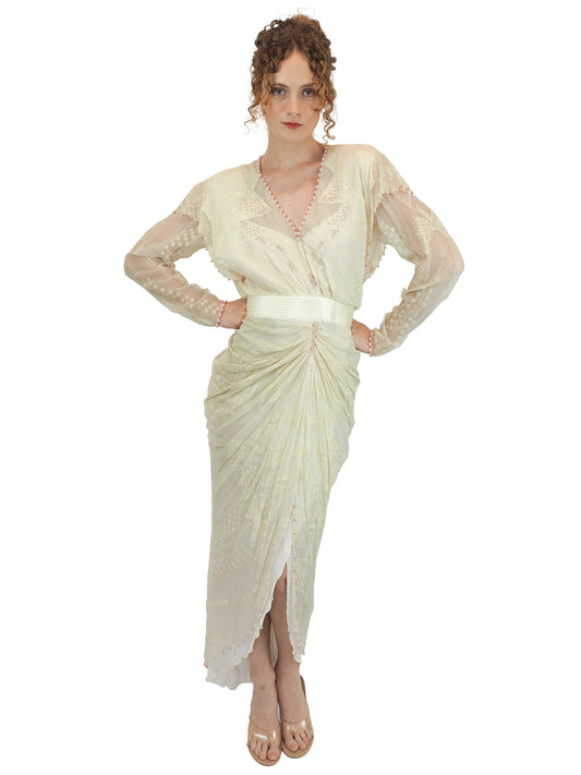 A vintage Zandra Rhodes cream-colored bridal wedding dress with sheer long sleeves, pink beaded detailing, a gathered waist, and a draped skirt