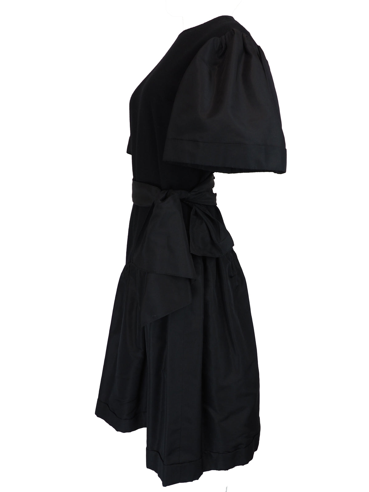 A black vintage 1980s pauline trigere dress with short puff sleeves, a matching waist belt, and a large bow detail at the side