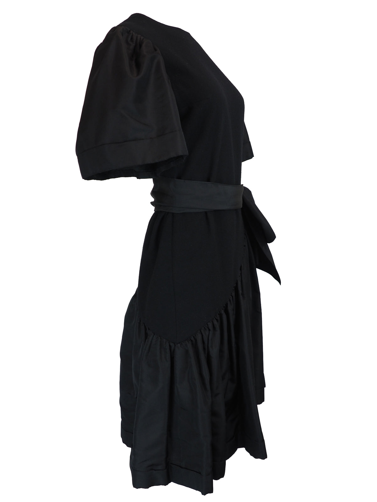 A black vintage 1980s pauline trigere dress with short puff sleeves, a matching waist belt, and a large bow detail at the side