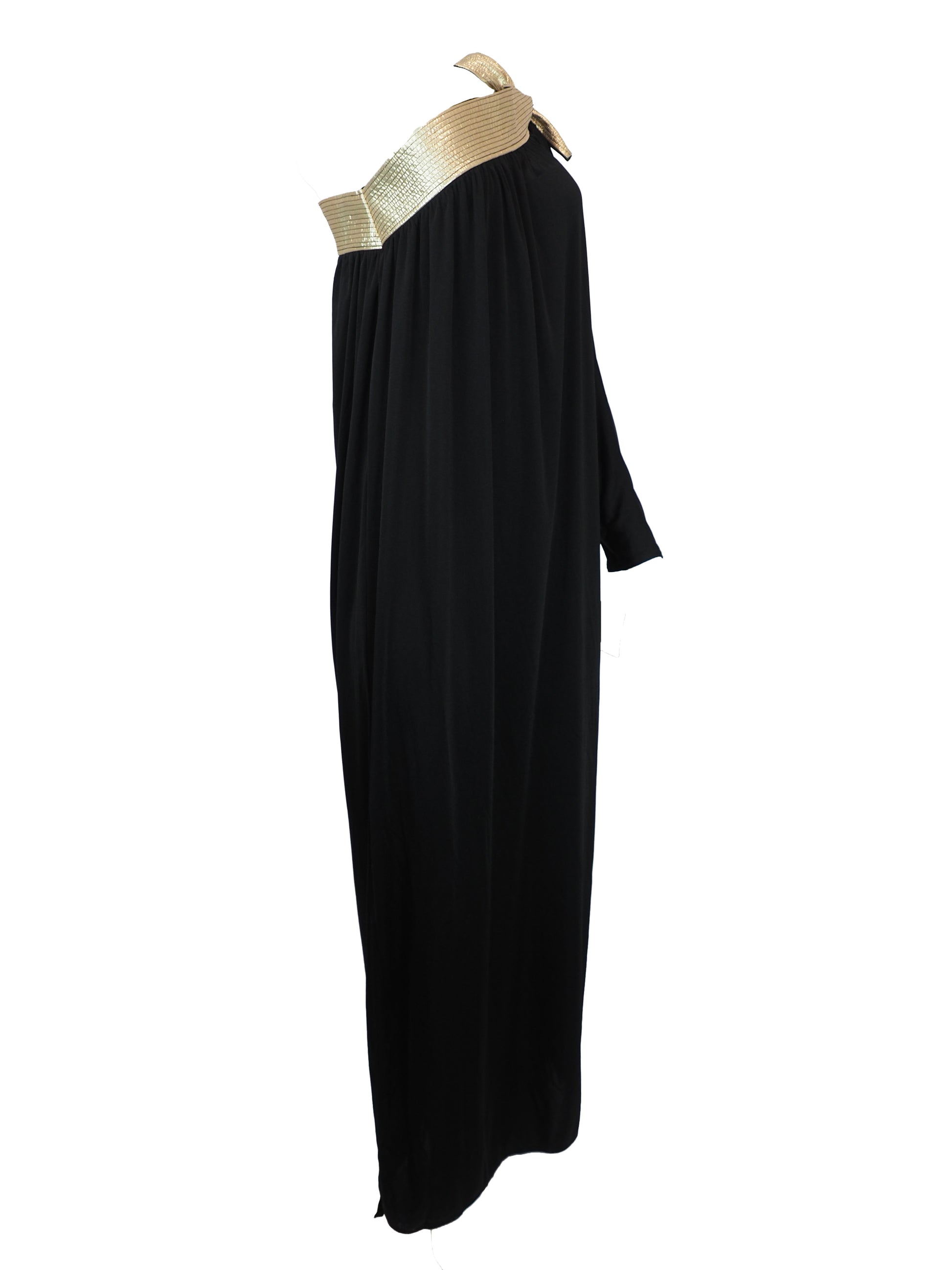 A vintage bill Tice black one-shoulder maxi dress with a wide, textured gold shoulder strap and a matching gold bow detail at the neckline