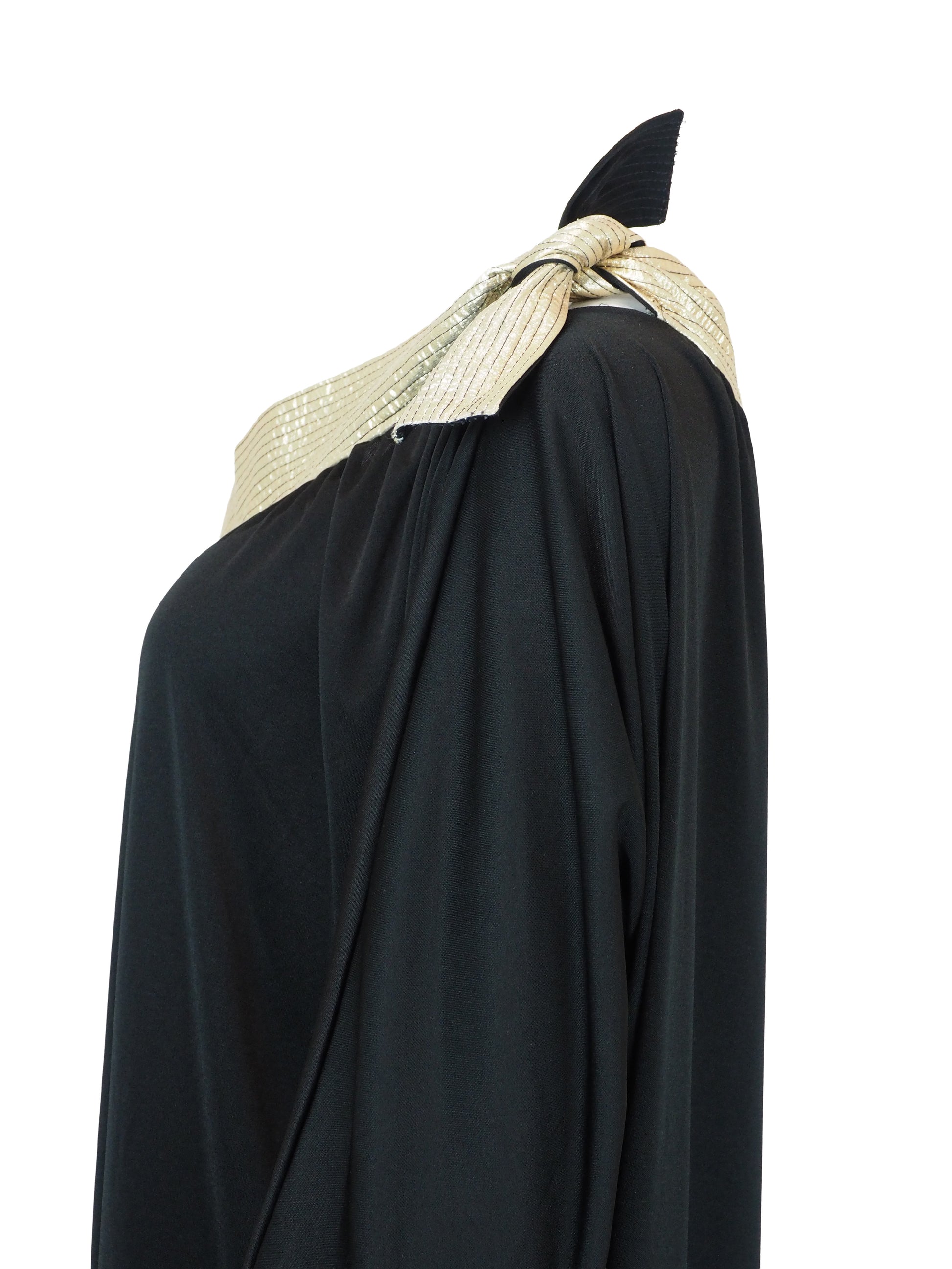 A vintage bill Tice black one-shoulder maxi dress with a wide, textured gold shoulder strap and a matching gold bow detail at the neckline