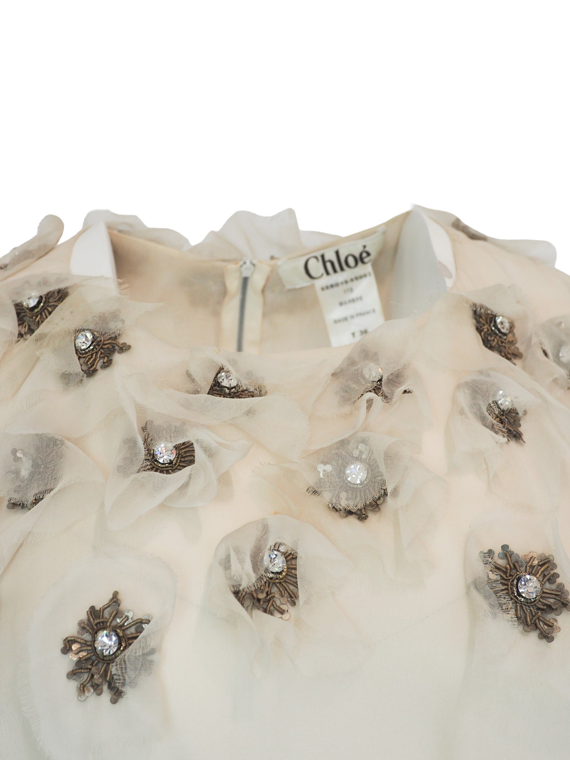 A vintage Chloe Y2K off-white sleeveless ruffled dress with floral embellishments on the bodice and a dark purple waist belt 