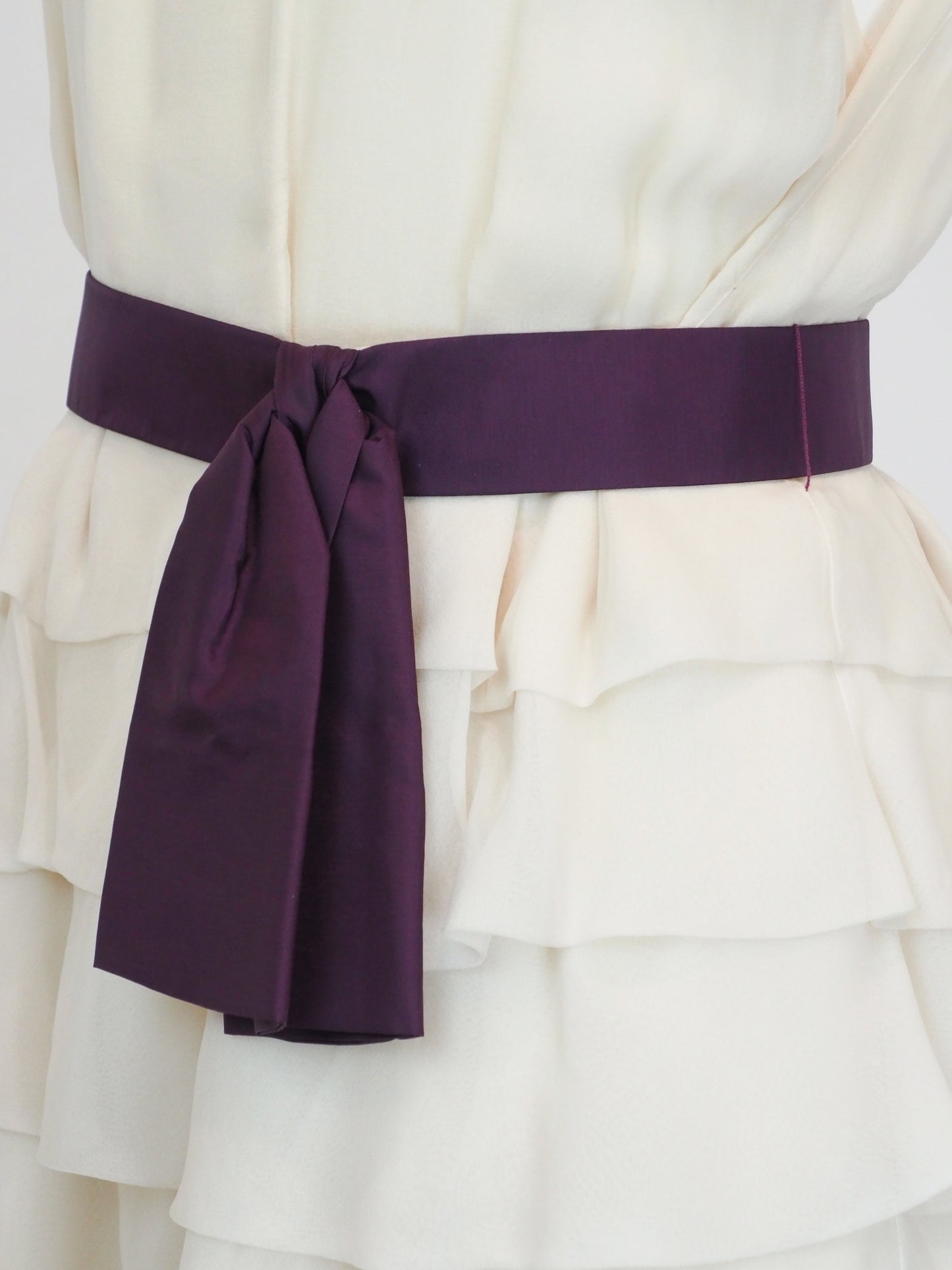 A vintage Chloe Y2K off-white sleeveless ruffled dress with floral embellishments on the bodice and a dark purple waist belt 
