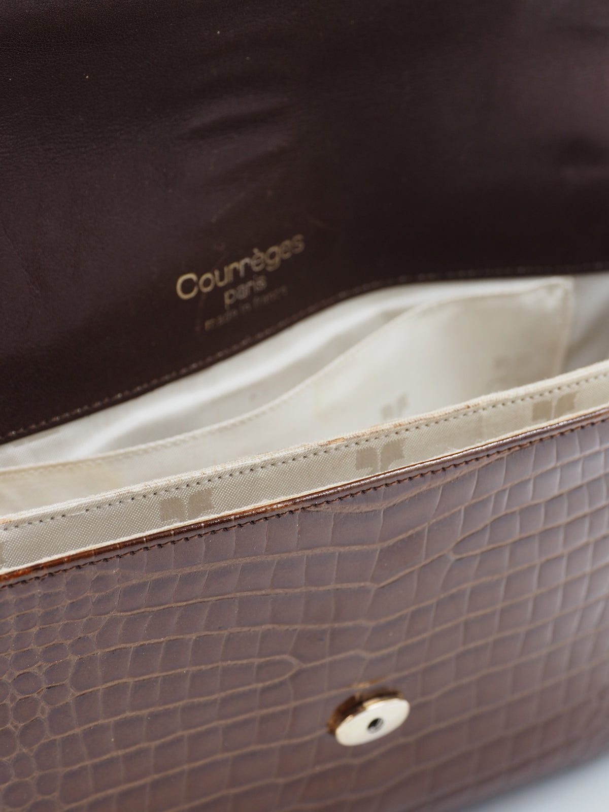 A dark brown courreges vintage crocodile-embossed leather shoulder bag with a matching adjustable strap and a small silver-tone metal logo on the front flap
