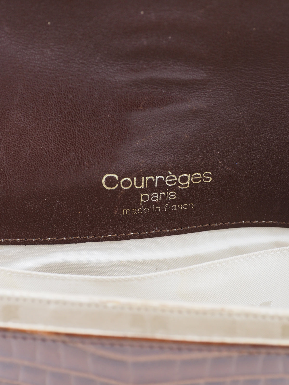 A dark brown courreges vintage crocodile-embossed leather shoulder bag with a matching adjustable strap and a small silver-tone metal logo on the front flap