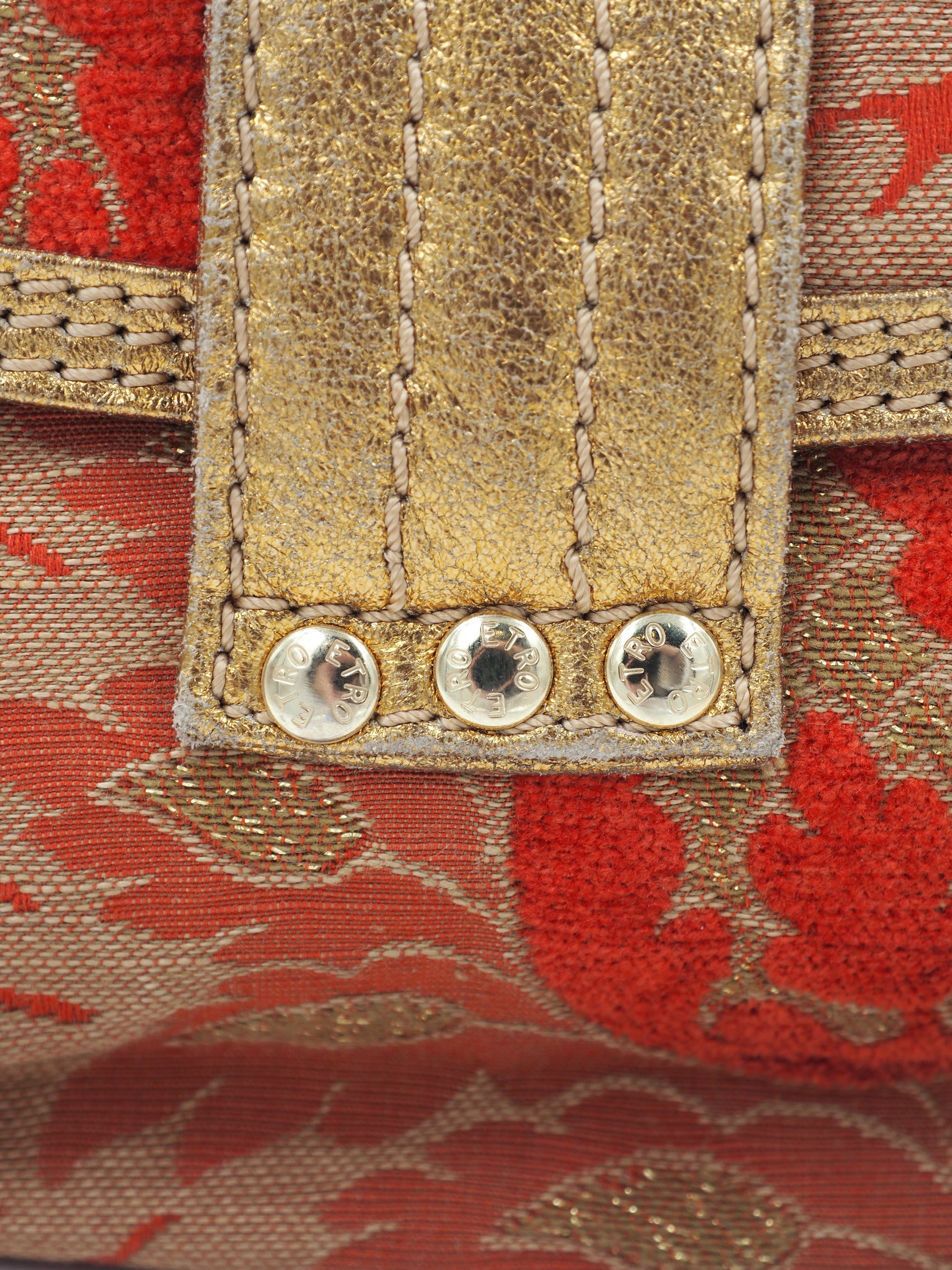 A vintage etro small shoulder bag with a red and gold floral jacquard pattern, featuring a gold-tone chain strap and a decorative red and gold clasp 