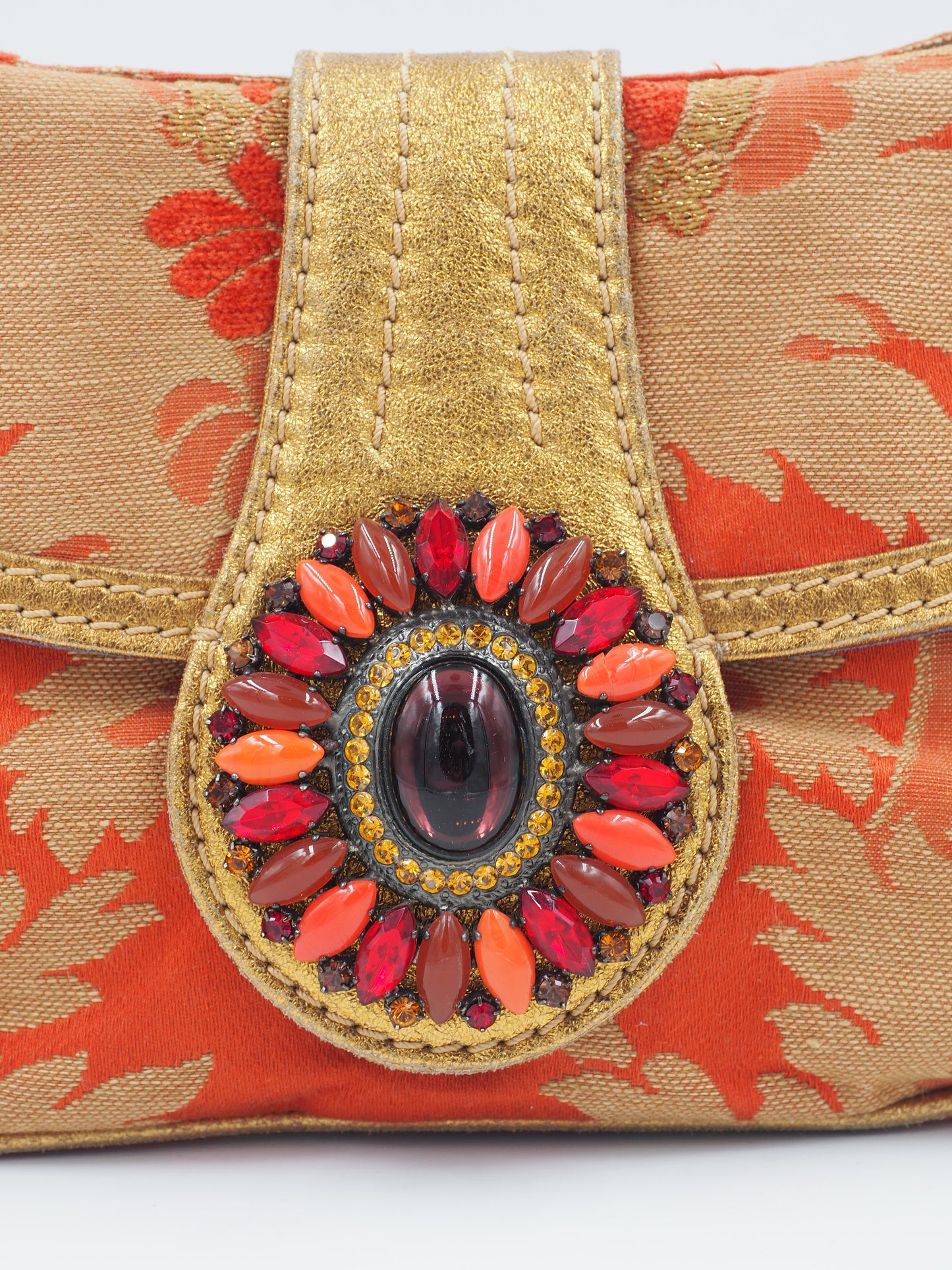 A vintage etro small shoulder bag with a red and gold floral jacquard pattern, featuring a gold-tone chain strap and a decorative red and gold clasp 