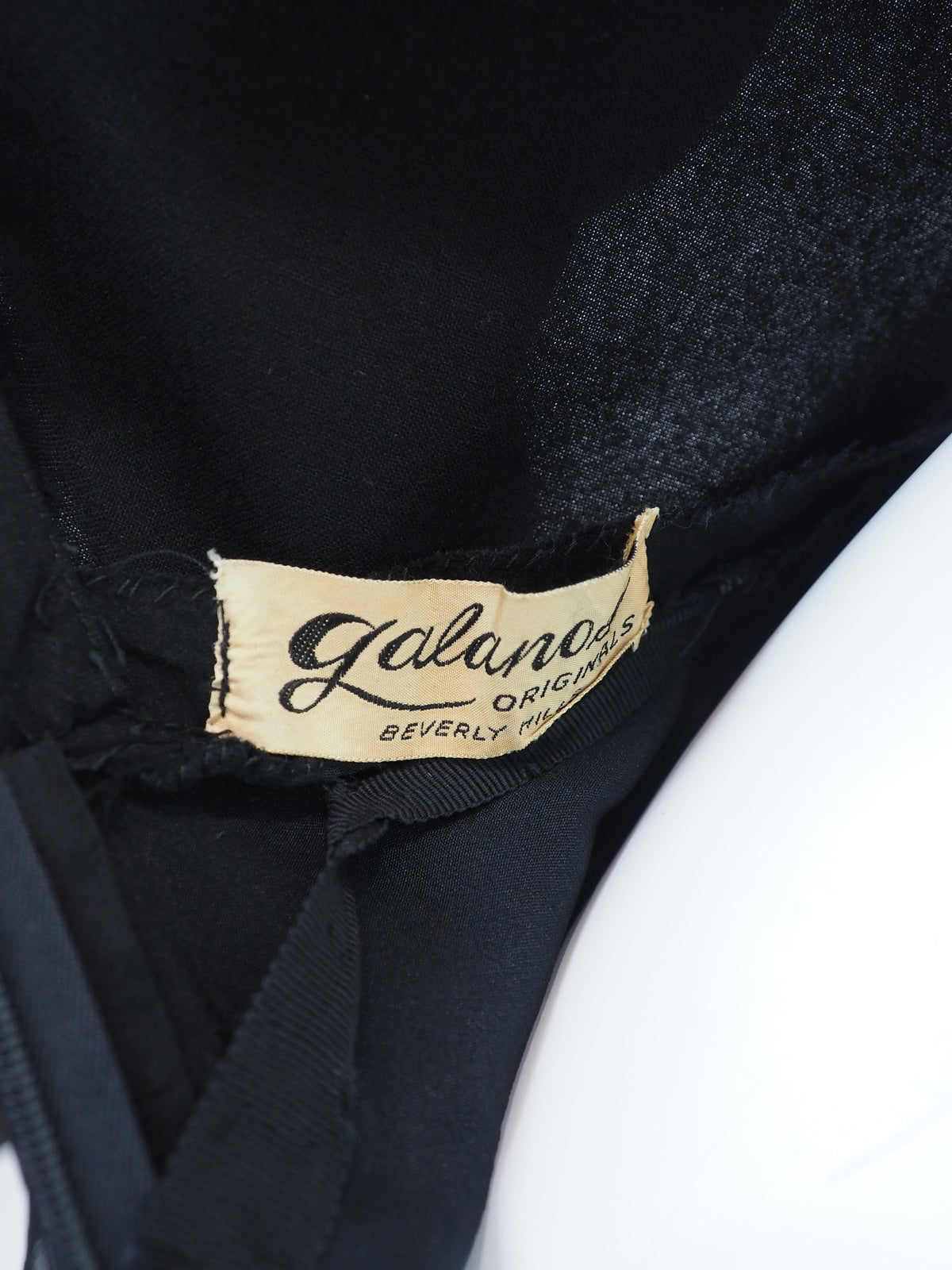 A vintage galanos black long-sleeve midi dress with a V-neckline, three-quarter button placket, and a pleated chiffon skirt