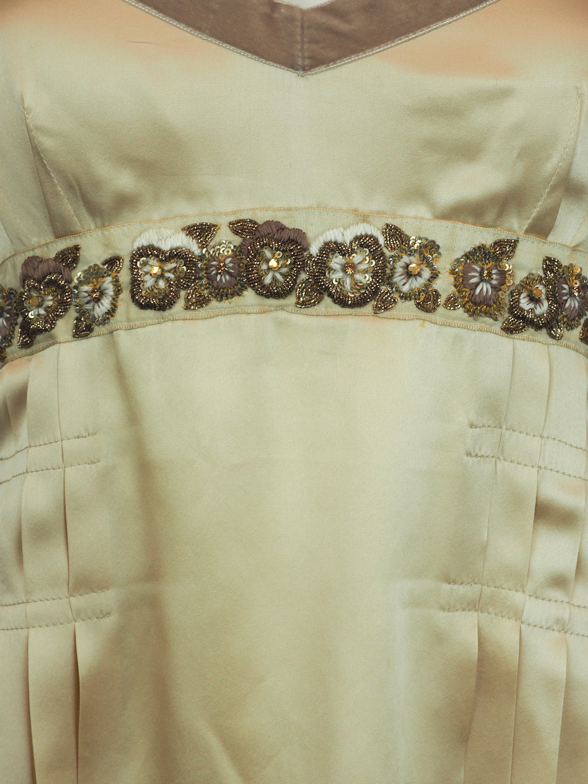 A vintage John galliano Y2K light beige satin camisole top with a V-neckline, thin shoulder straps, a decorative floral embroidered waistband, and pleated detailing on the front
