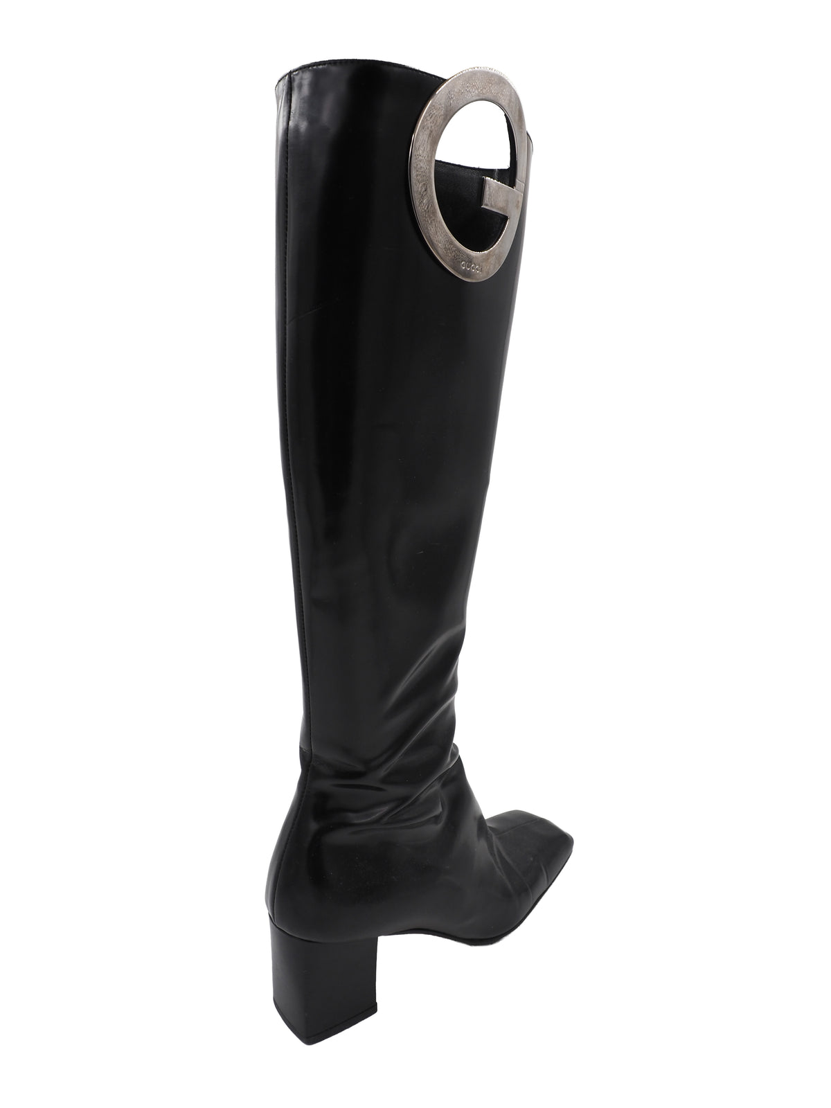 A vintage gucci 1990s black leather knee-high boot with a chunky block heel and a large circular silver-tone metal ring logo detail near the top shaft