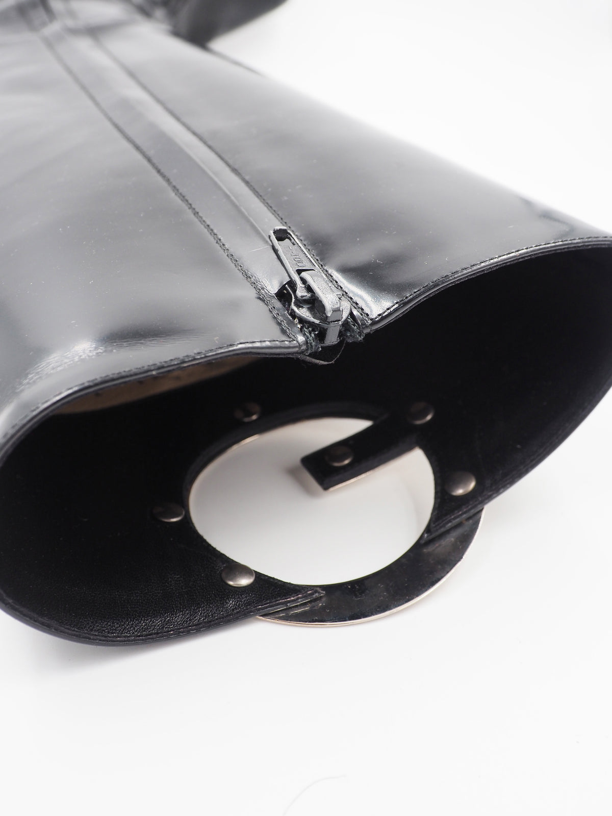 A vintage gucci 1990s black leather knee-high boot with a chunky block heel and a large circular silver-tone metal ring logo detail near the top shaft