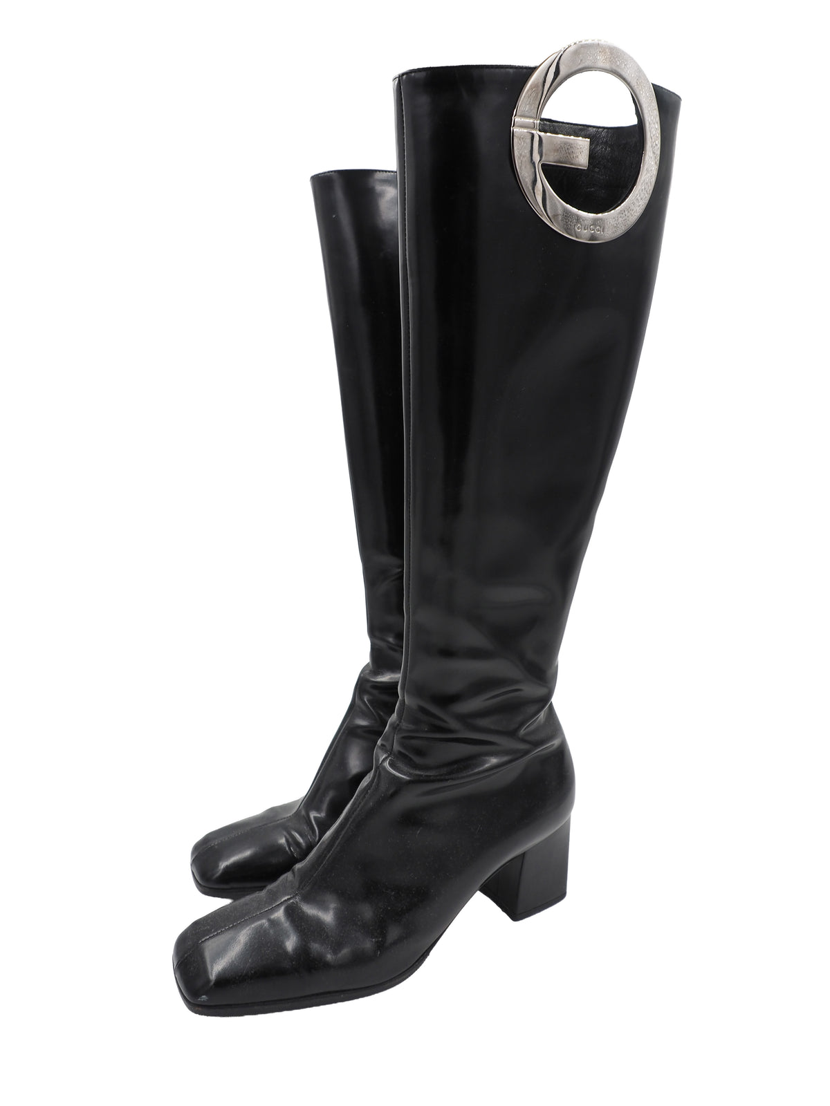 A vintage gucci 1990s black leather knee-high boot with a chunky block heel and a large circular silver-tone metal ring logo detail near the top shaft
