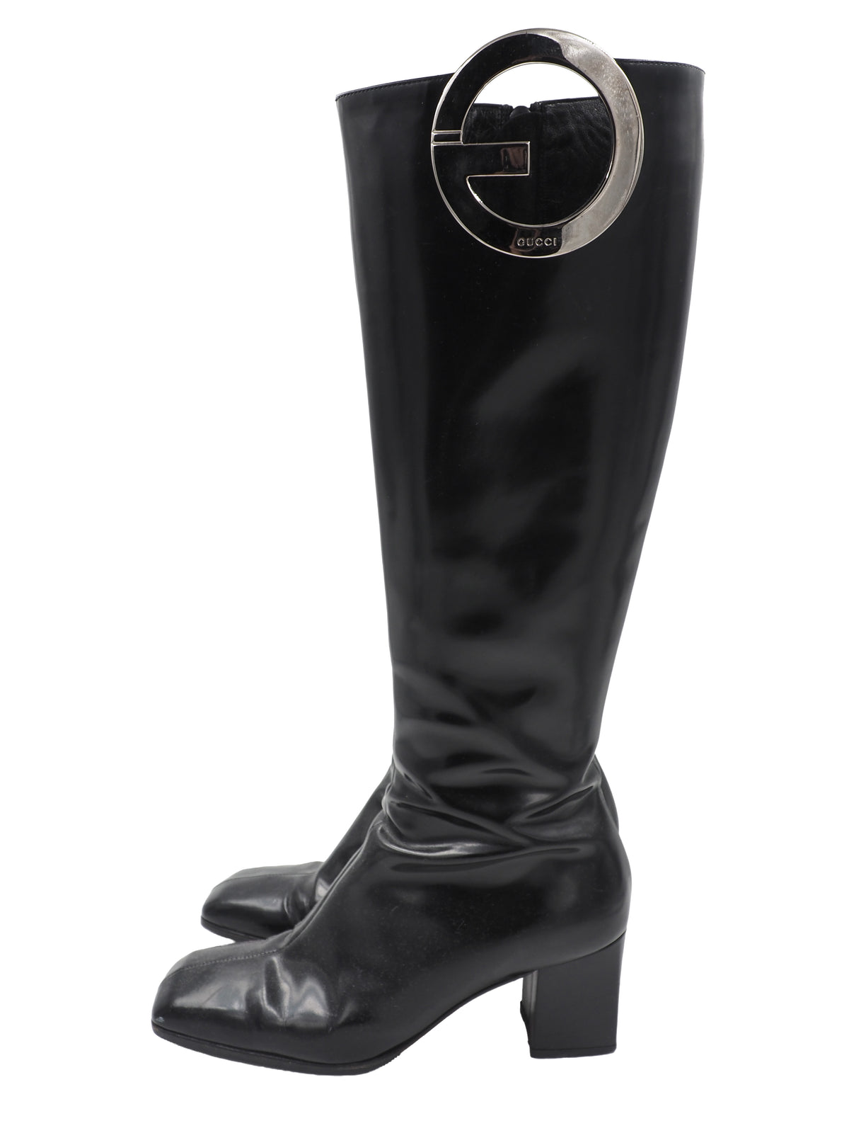 A vintage gucci 1990s black leather knee-high boot with a chunky block heel and a large circular silver-tone metal ring logo detail near the top shaft
