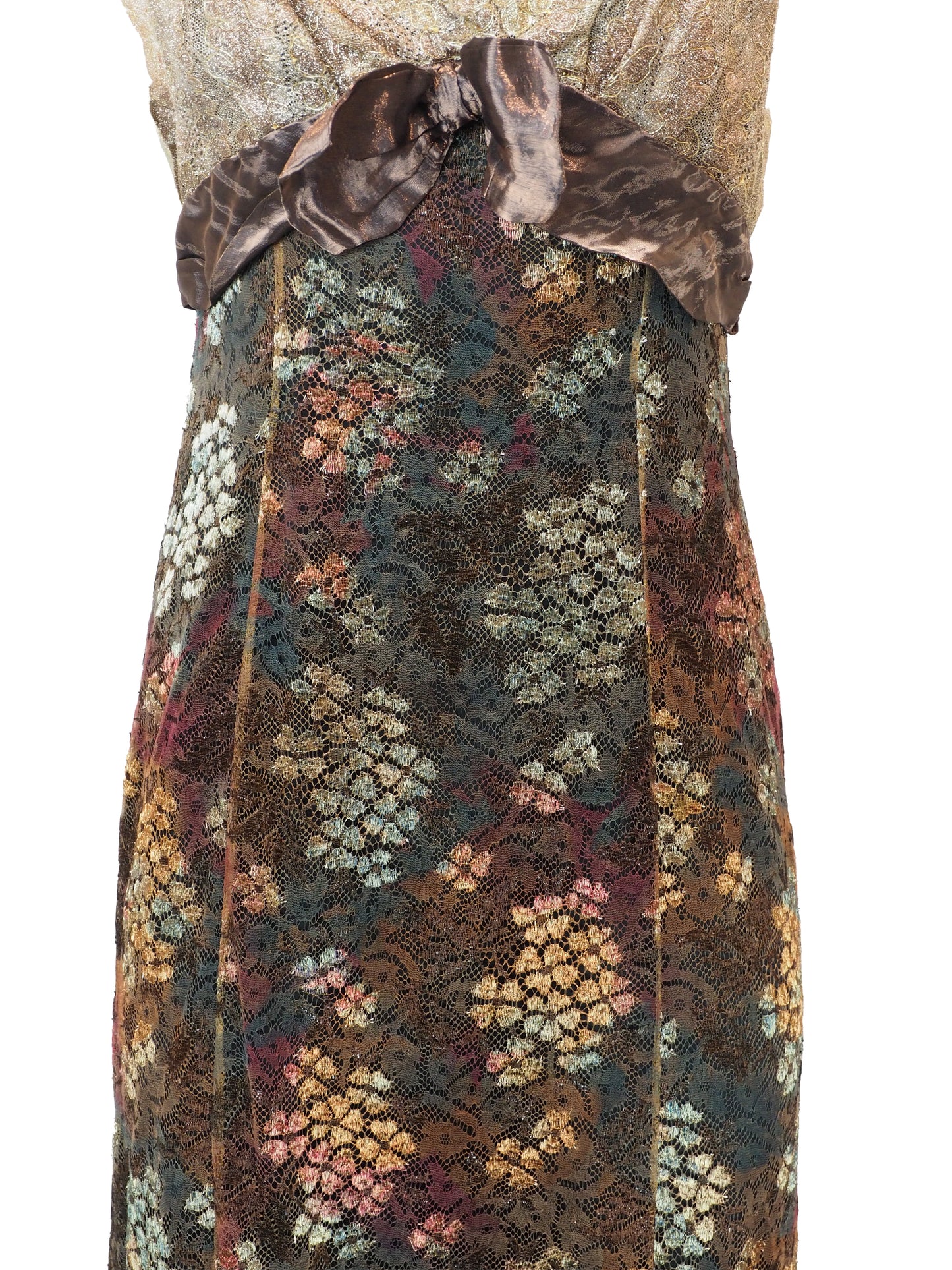 A vintage christian Lacroix runway sleeveless maxi dress with a sheer floral lace pattern in earthy tones of brown, green, and gold, featuring a cream lace bodice and a dark brown satin waist tie