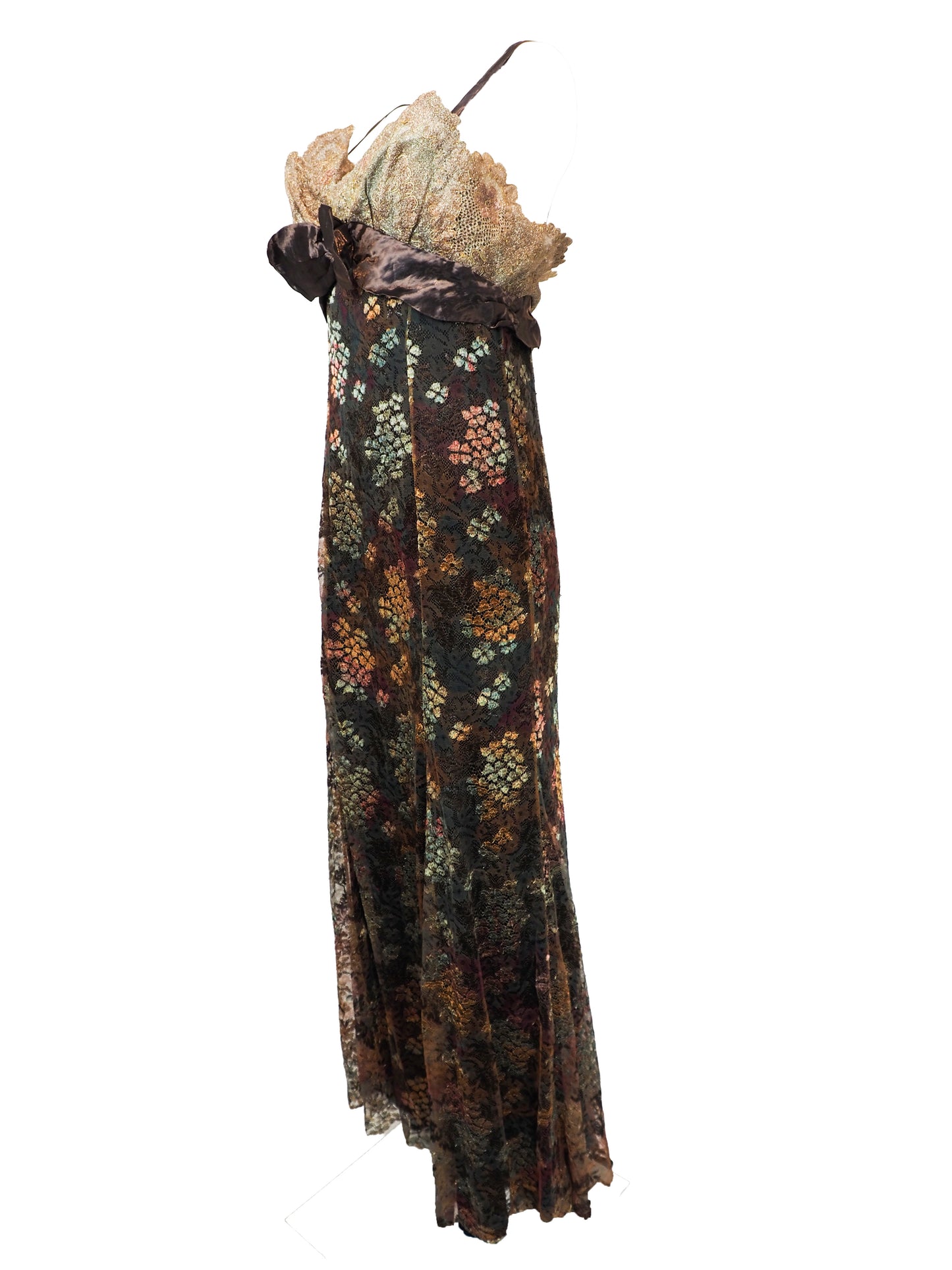 A vintage christian Lacroix runway sleeveless maxi dress with a sheer floral lace pattern in earthy tones of brown, green, and gold, featuring a cream lace bodice and a dark brown satin waist tie