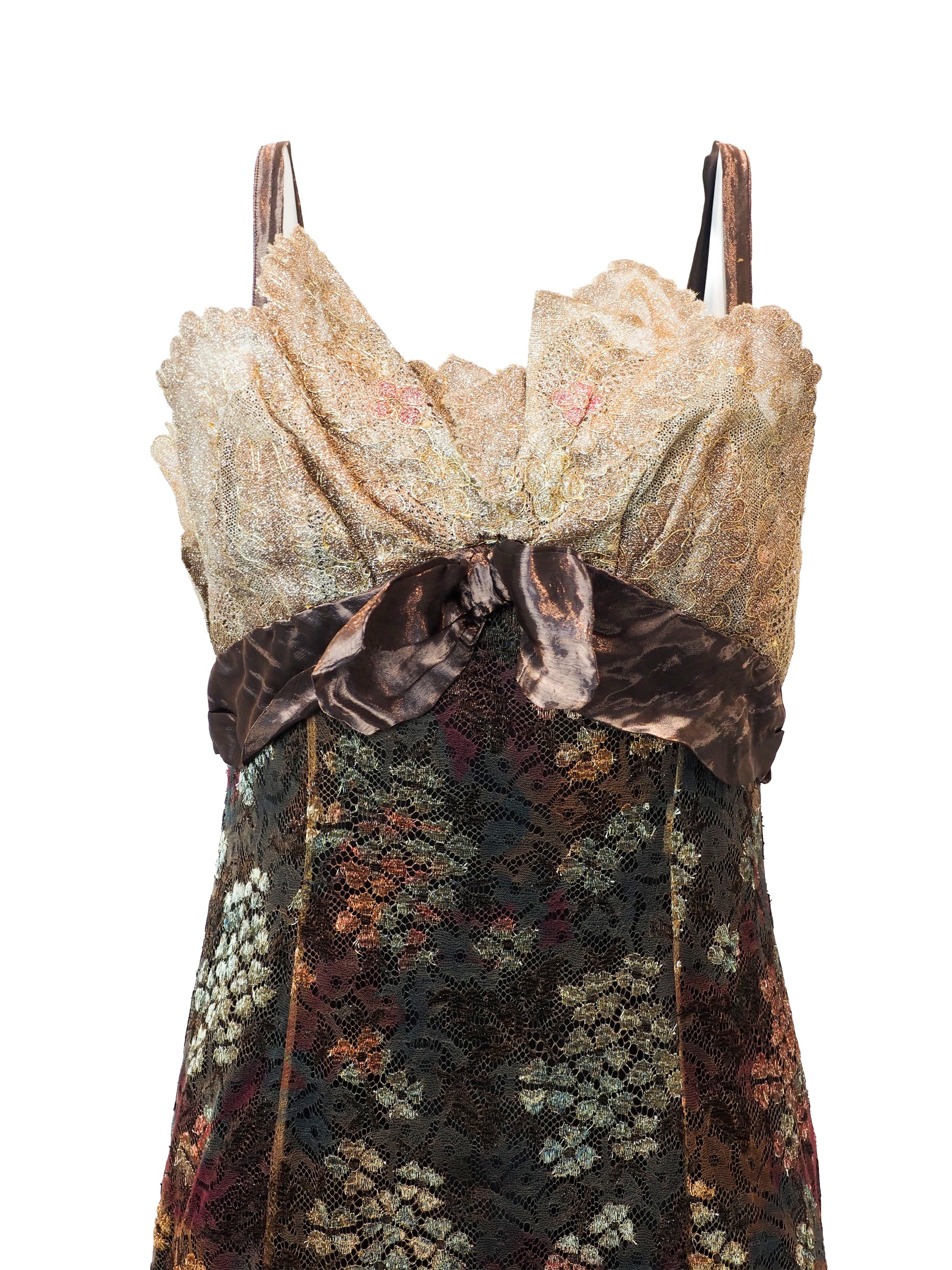 A vintage christian Lacroix runway sleeveless maxi dress with a sheer floral lace pattern in earthy tones of brown, green, and gold, featuring a cream lace bodice and a dark brown satin waist tie