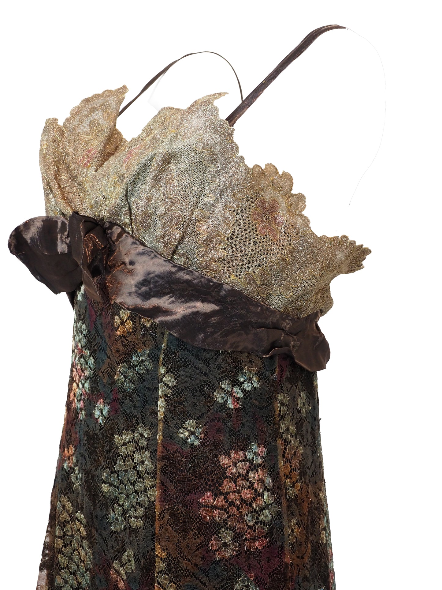 A vintage christian Lacroix runway sleeveless maxi dress with a sheer floral lace pattern in earthy tones of brown, green, and gold, featuring a cream lace bodice and a dark brown satin waist tie