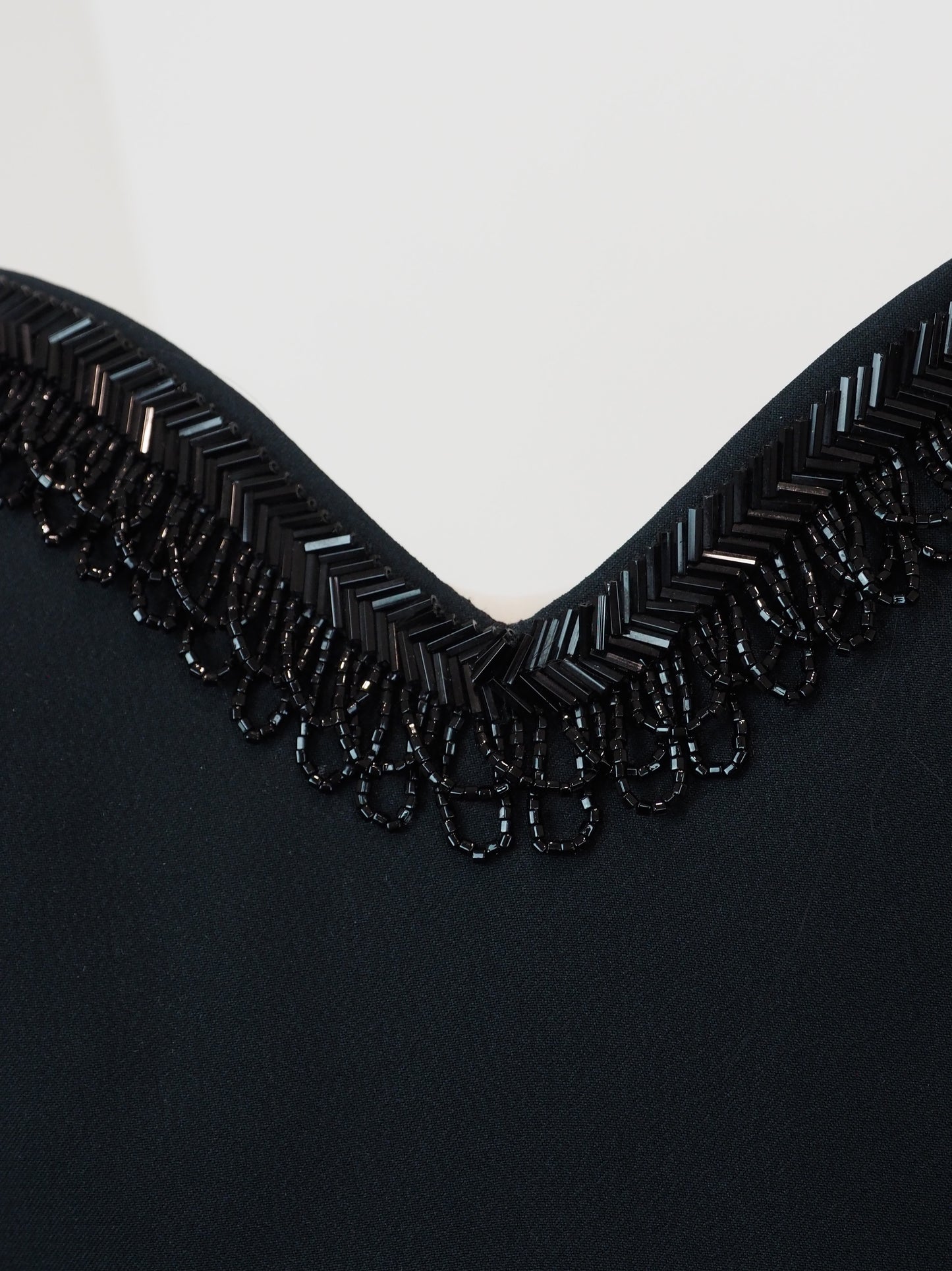 A vintage moschino black camisole top with thin spaghetti straps and a sweetheart neckline, decorated with black beaded fringe trim along the neckline 