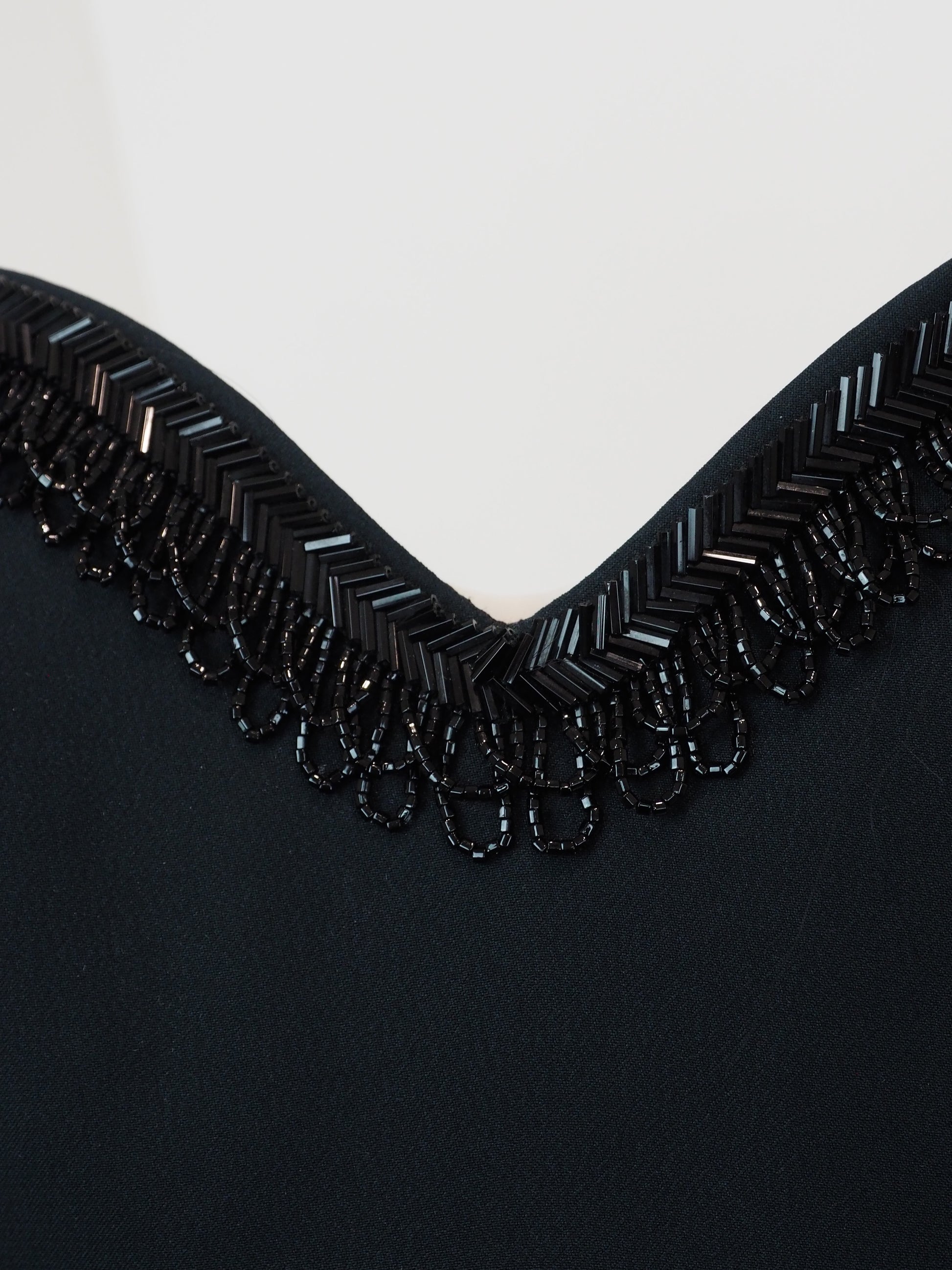 A vintage moschino black camisole top with thin spaghetti straps and a sweetheart neckline, decorated with black beaded fringe trim along the neckline 
