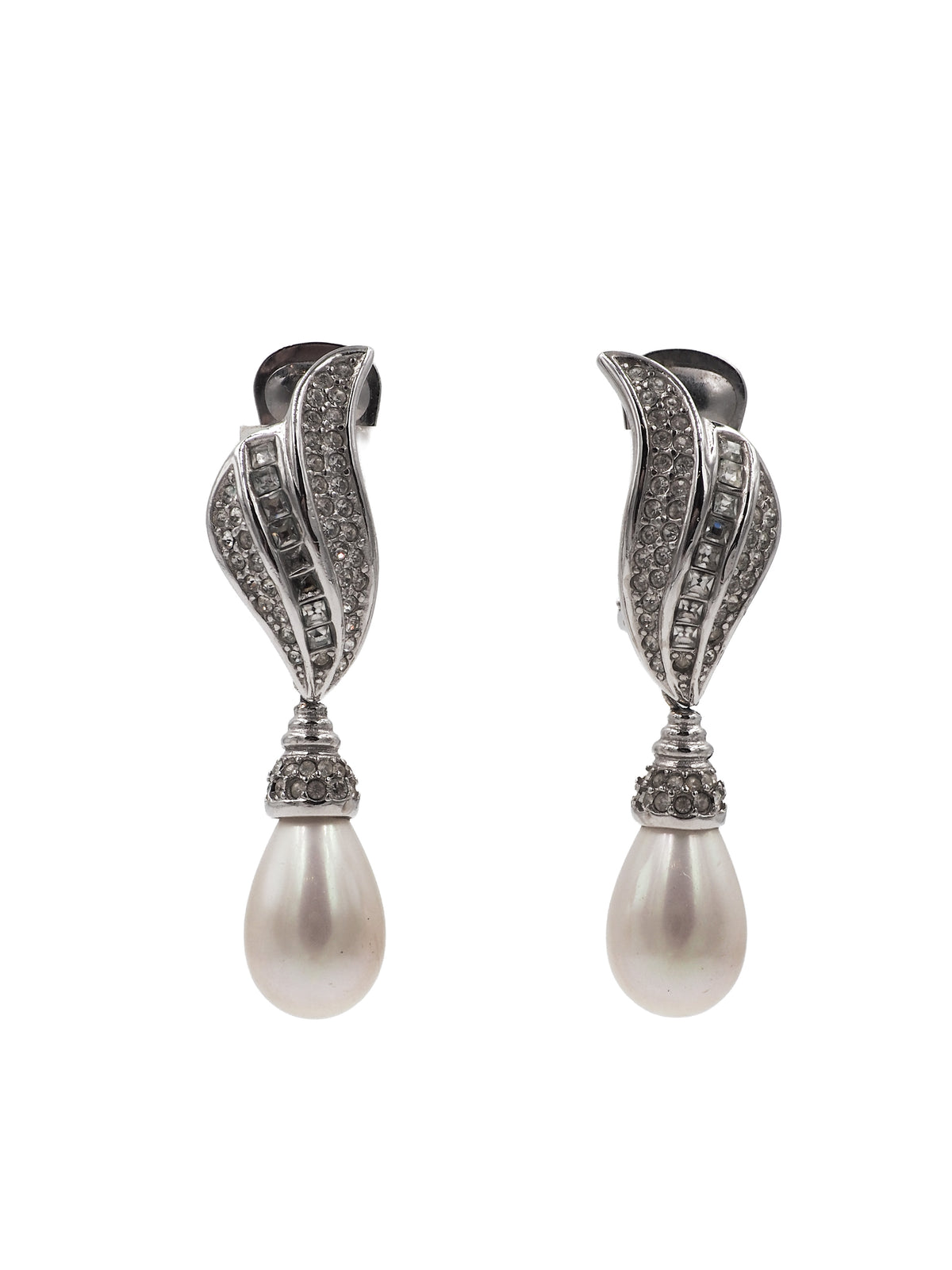 A pair of silver-toned drop earrings featuring a curved, pavé-set crystal design above a teardrop-shaped white pearl