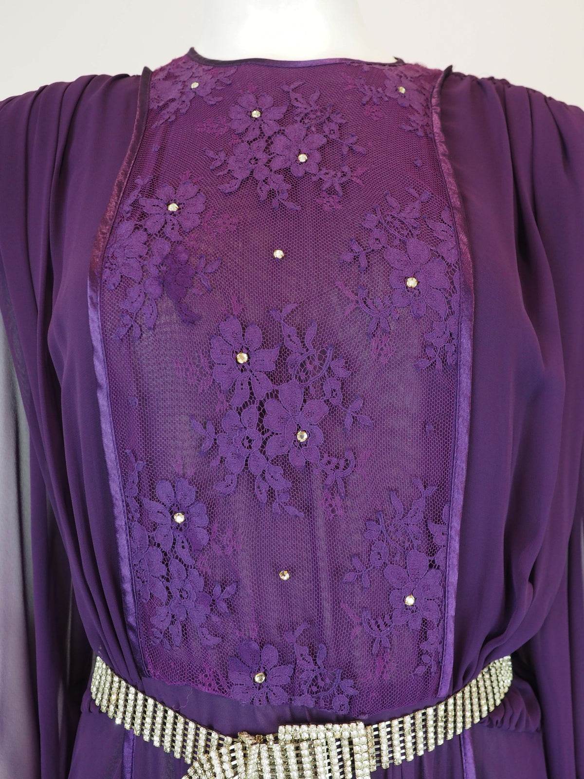 A vintage long-sleeved purple maxi dress with a sheer mesh overlay, a sequined embroidered bodice, and a silver rhinestone-embellished belt