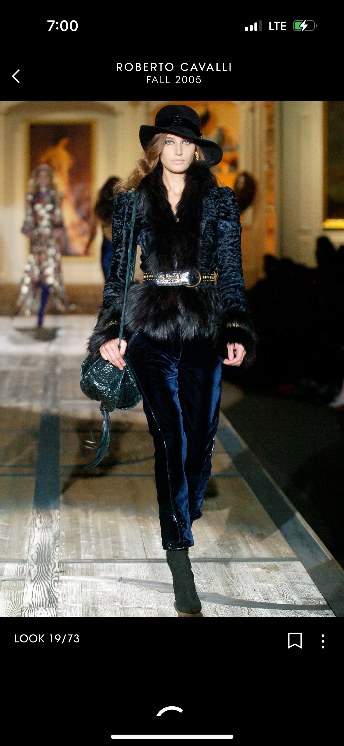 Model walking on a runway wearing a dark outfit with fur details, part of Roberto Cavalli's Fall 2005 collection.