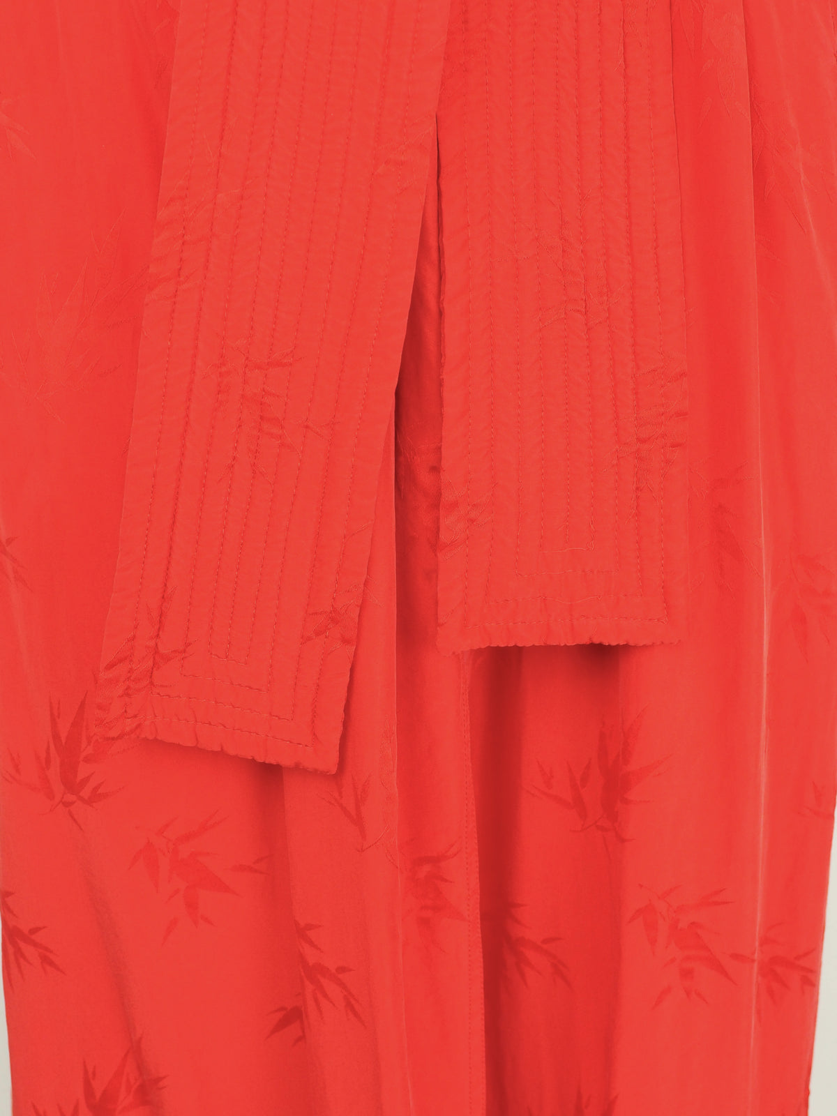 A vibrant red wrap robe with a matching waist tie belt, featuring a subtle tonal floral jacquard pattern near the lower hem